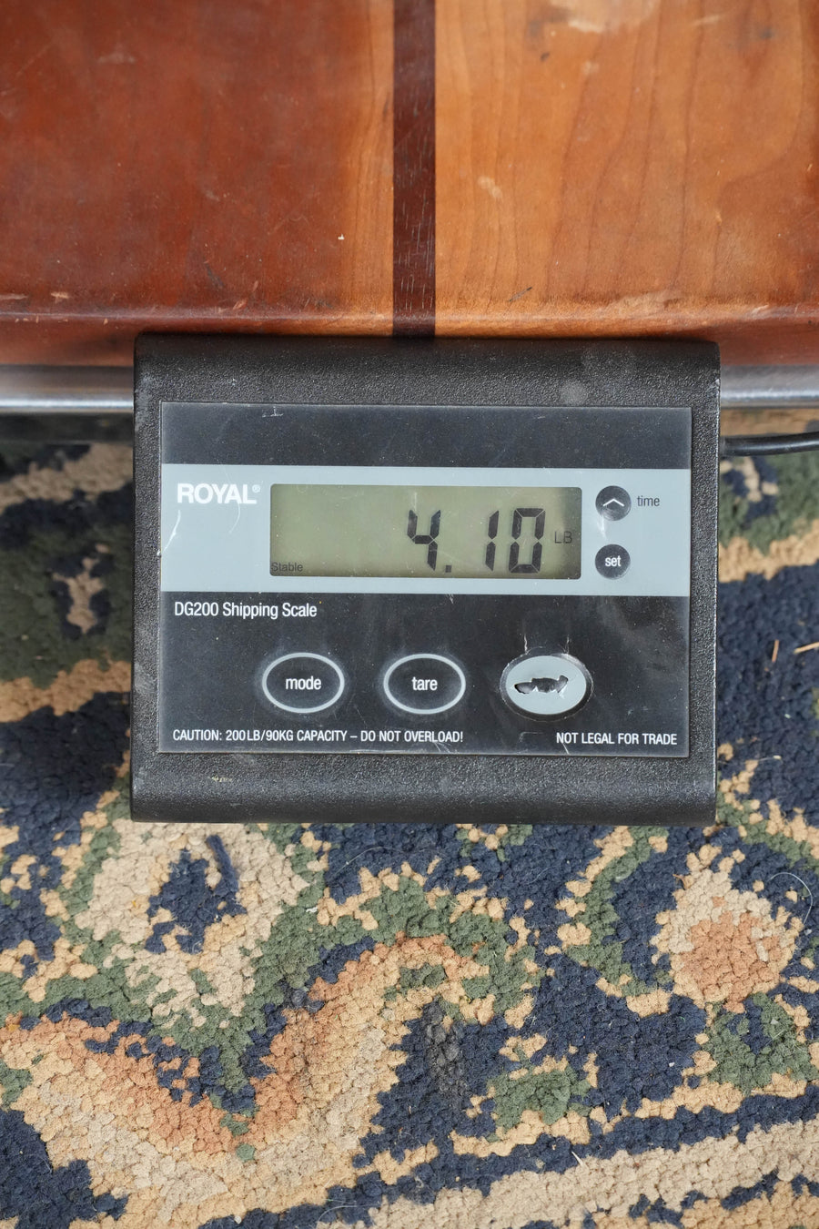 A Royal DG200 shipping scale displays 4.10 LB, set on a patterned rug under wood that echoes the satin finish of a Martin & Co. D-28 Satin Spruce/Rosewood Acoustic Guitar #3679.