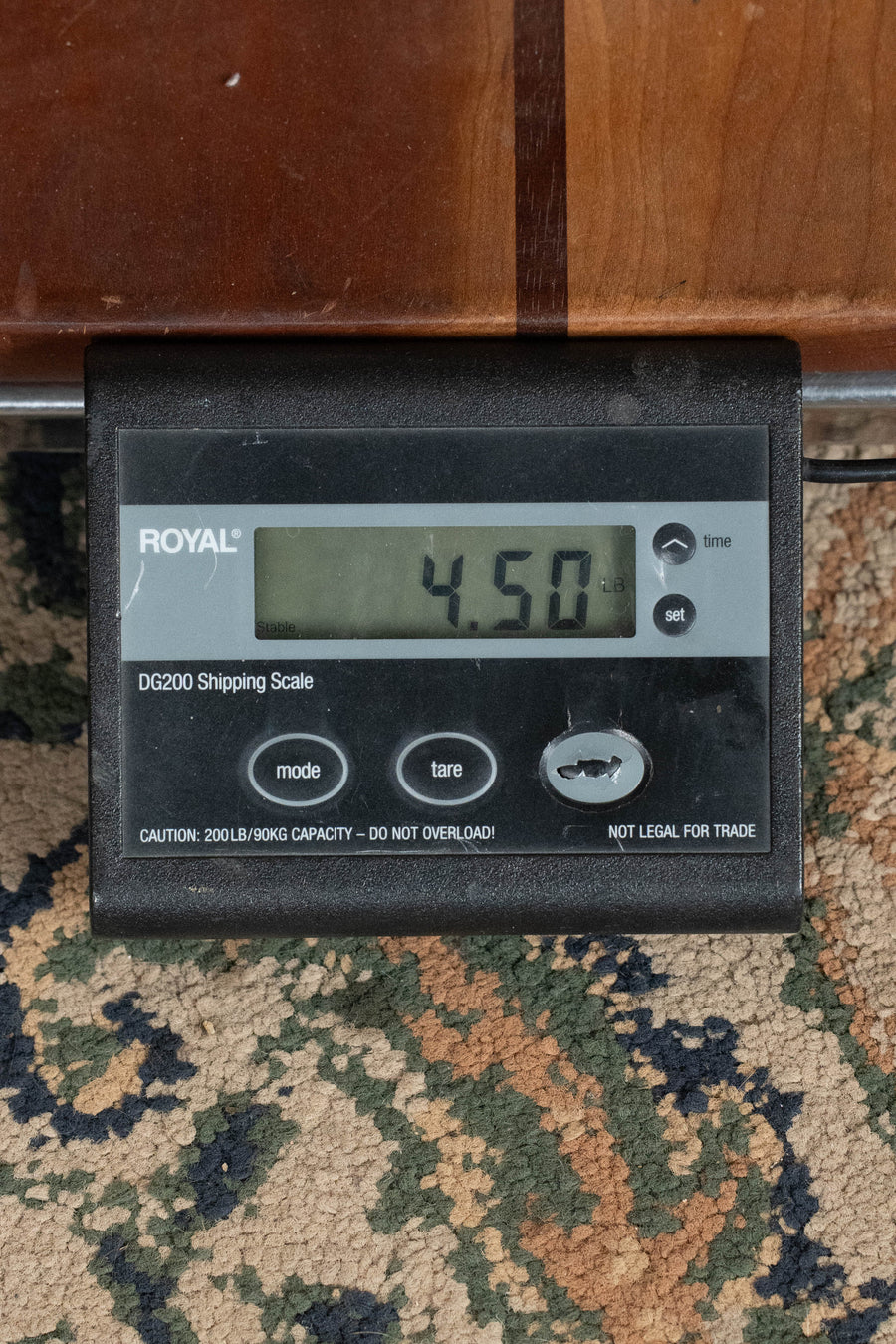 A digital shipping scale reads 4.50 pounds on a patterned carpet, with part of the Martin & Co. D-X2E Billy Strings Spruce/HPL Rosewood Dreadnought Guitar w/Martin Electronics (#6319) visible above it.