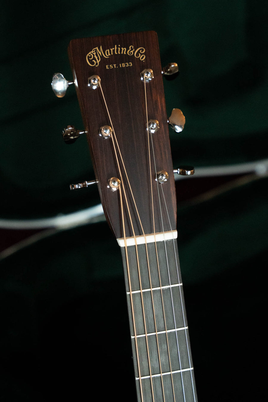Close-up of the headstock of a Martin & Co. HD-28 Spruce/East Indian Rosewood Dreadnought Acoustic Guitar #8326, displaying tuning pegs, strings, and the Martin & Co. EST. 1833 logo on dark wood against a blurred background.