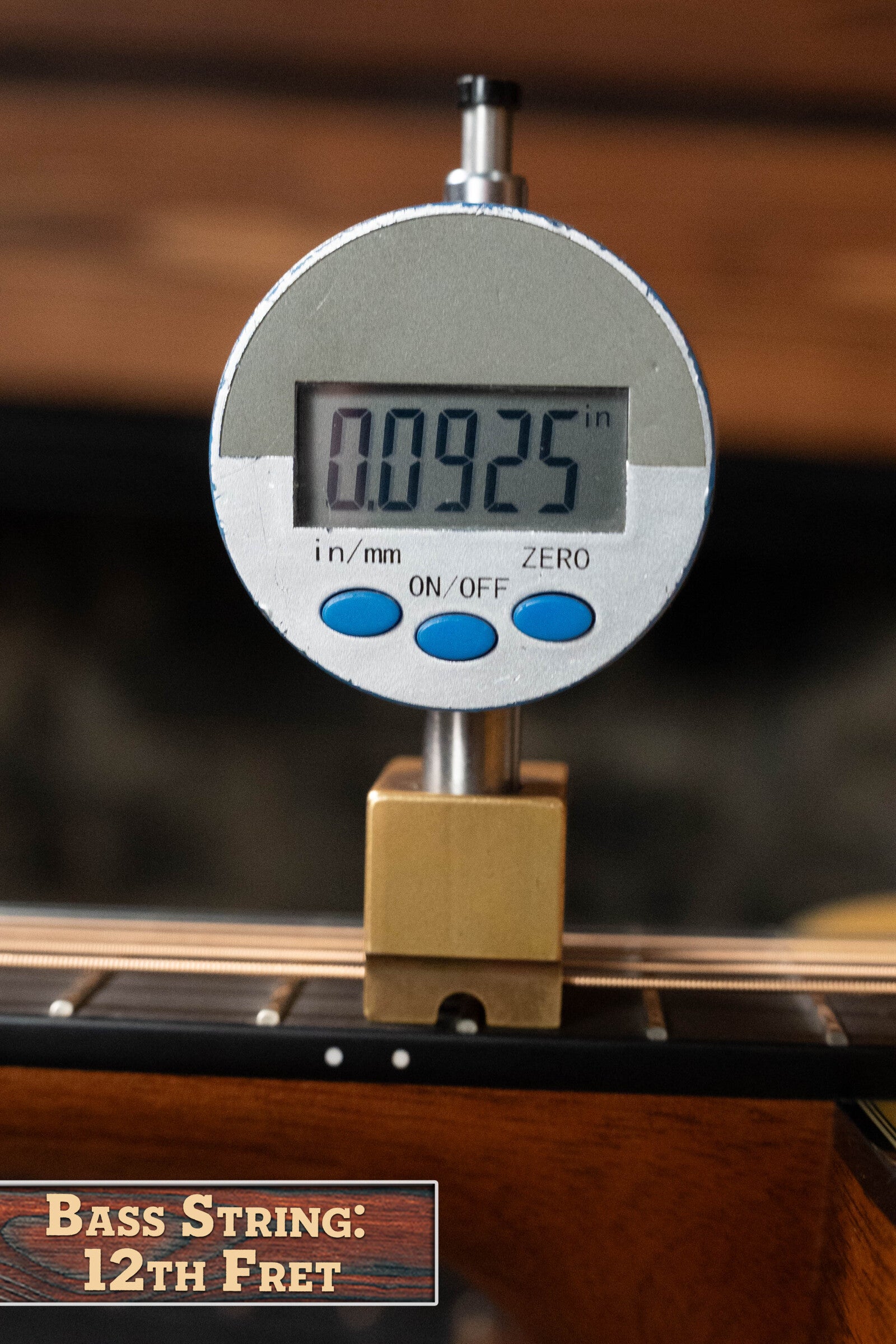 A digital gauge measures the bass string height at the 12th fret on a Martin & Co. Custom Shop D-18V Adirondack/Mahogany Dreadnought Acoustic Guitar #6905, showing 0.0925 inches. A wooden label reads: Bass String: 12th Fret.