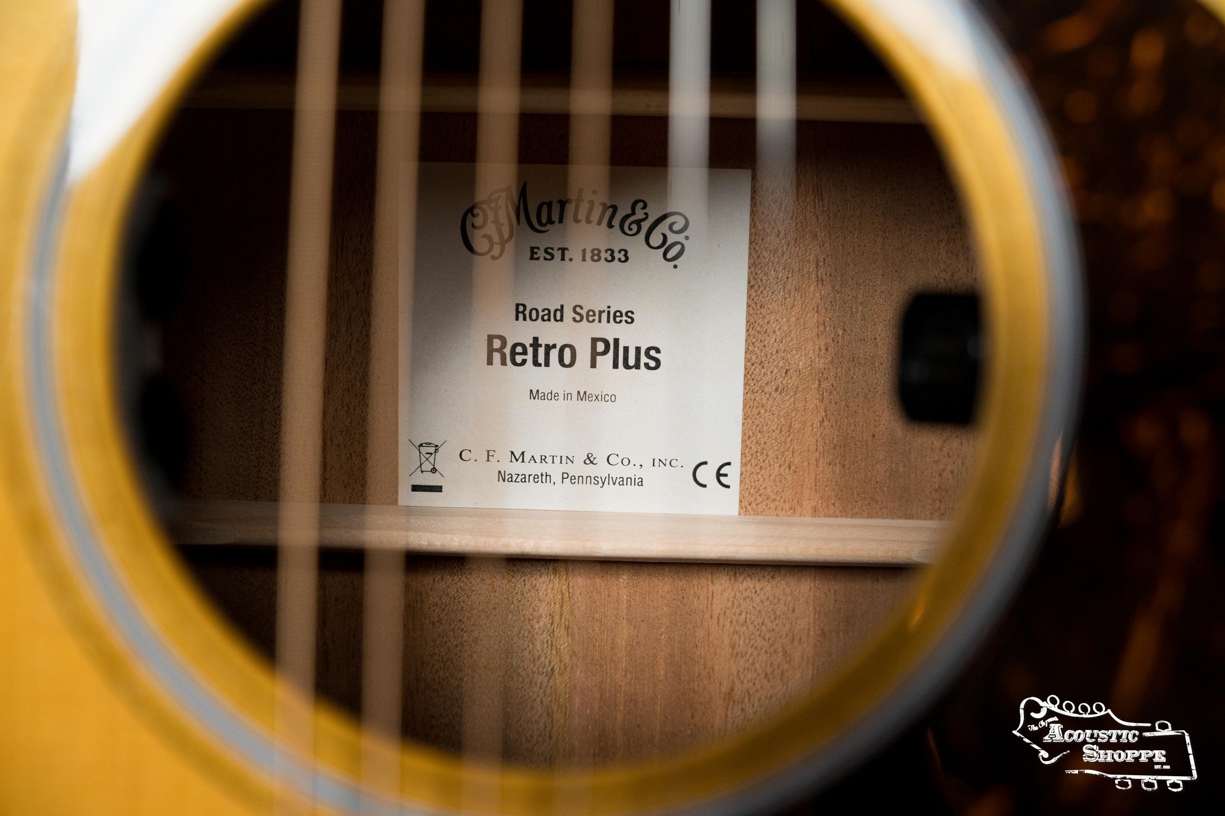Close-up through the strings shows a Martin & Co. DE Retro Plus Torrefied Spruce/Mahogany Dreadnought Guitar w/Martin Electronics #0808 label, made in Mexico. The Acoustic Shoppe logo appears at the lower right.