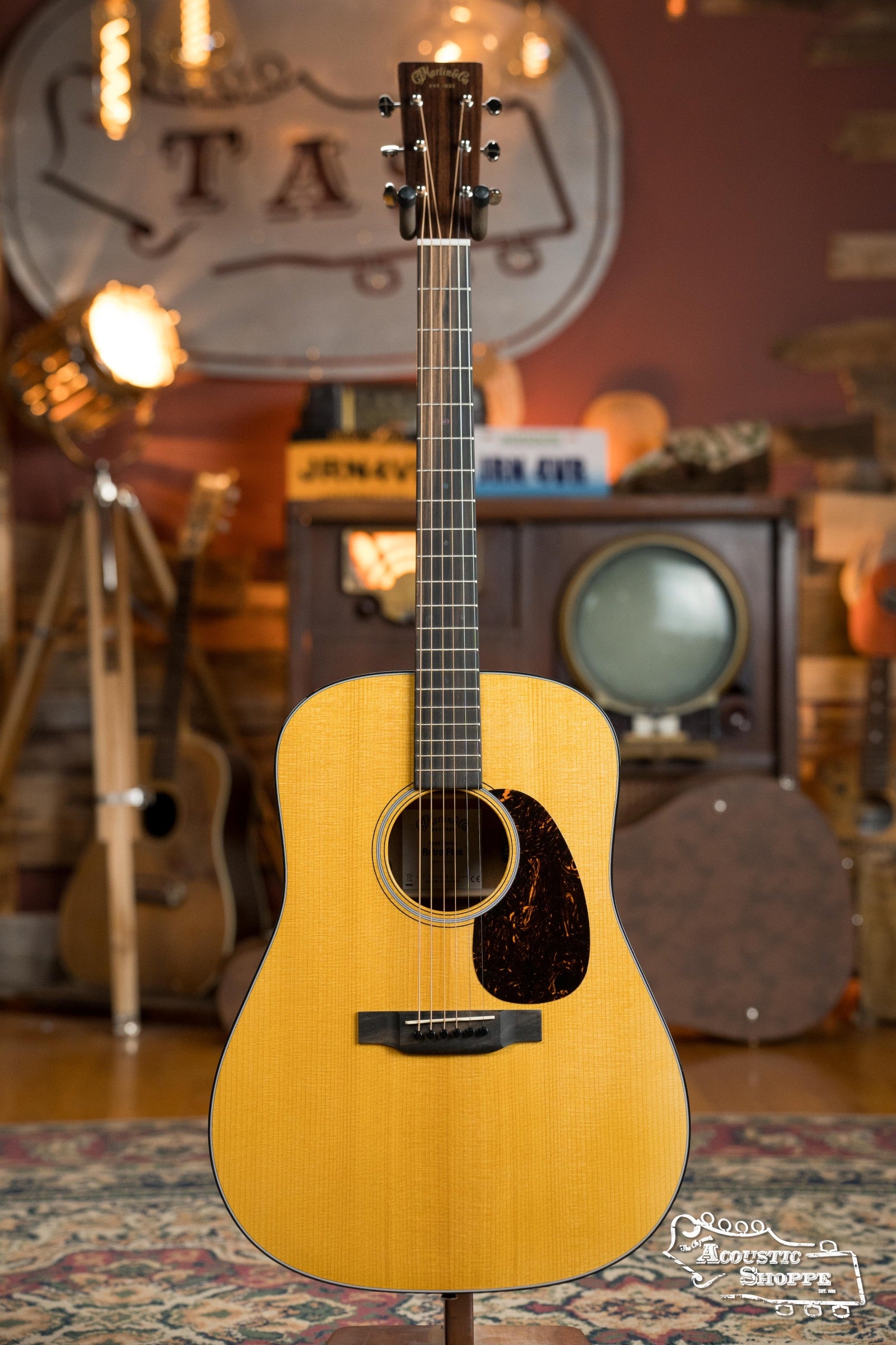 The Martin & Co. DE Retro Plus Torrefied Spruce/Mahogany Dreadnought Guitar w/Martin Electronics #0808 stands upright on a patterned rug, surrounded by vintage gear and warm lighting in a cozy, retro-inspired room.