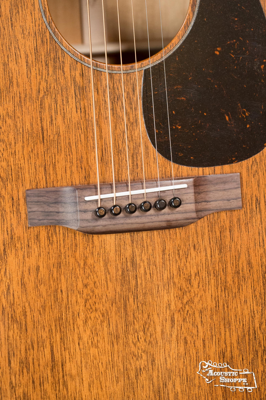 Close-up of the Martin & Co. D-15M All Mahogany Dreadnought Acoustic Guitar #1493, highlighting its wooden body, six-string bridge with black pins, and part of the black pickguard.