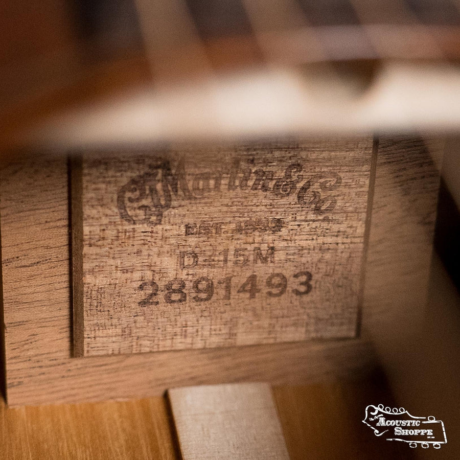 Close-up of a wooden label inside a Martin & Co. D-15M All Mahogany Dreadnought Acoustic Guitar #1493, featuring the Martin & Co. logo and model info. The Acoustic Shoppe logo is visible in the bottom right corner.