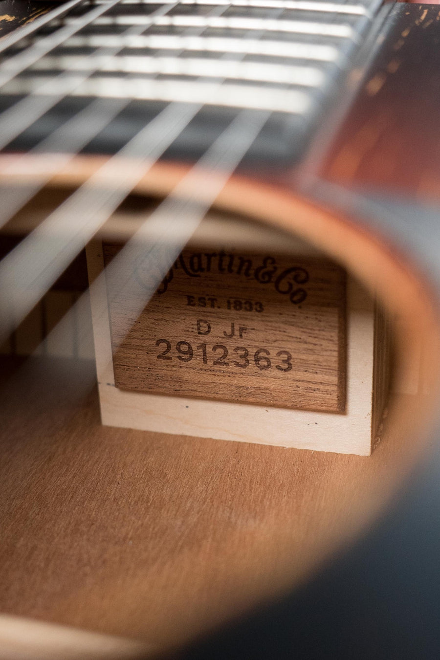 Close-up of the Martin & Co. label and serial number #2363 inside a Martin D Jr E Streetlegend Burst Spruce/Sapele Aged-Look Dreadnought Guitar, seen through the strings and sound hole.