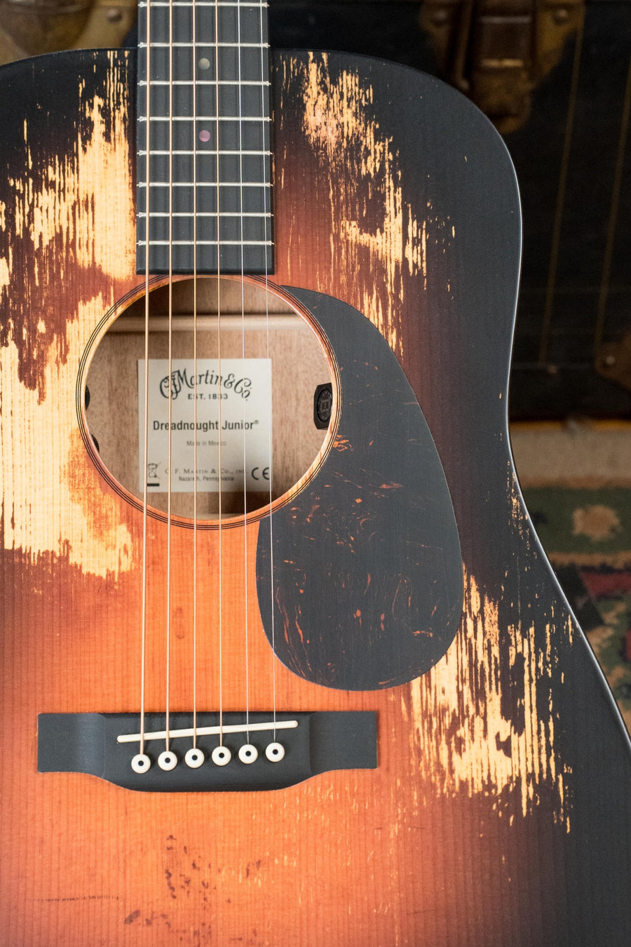 Close-up of the *New 2025 Model* Martin & Co. D Jr E Streetlegend Burst, a compact dreadnought guitar with an aged-look spruce/sapele finish, six strings, visible bridge, and built-in Martin electronics.