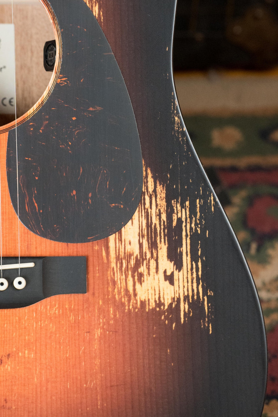 Close-up of the *New 2025 Model* Martin & Co. D Jr E Streetlegend Burst Spruce/Sapele Aged-Look Dreadnought Guitar w/Martin Electronics #3849, with sunburst finish and exposed wood, on a patterned rug background.
