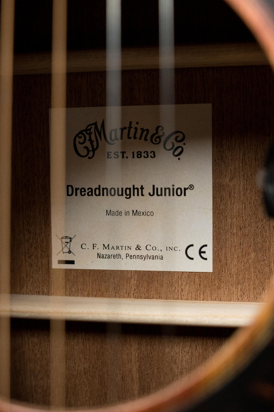 Close-up of the *New 2025 Model* Martin D Jr E Streetlegend Burst Spruce/Sapele Aged-Look Dreadnought Guitar by Martin & Co., showing the label inside—“Dreadnought Junior, Made in Mexico”—visible through the sound hole and strings.