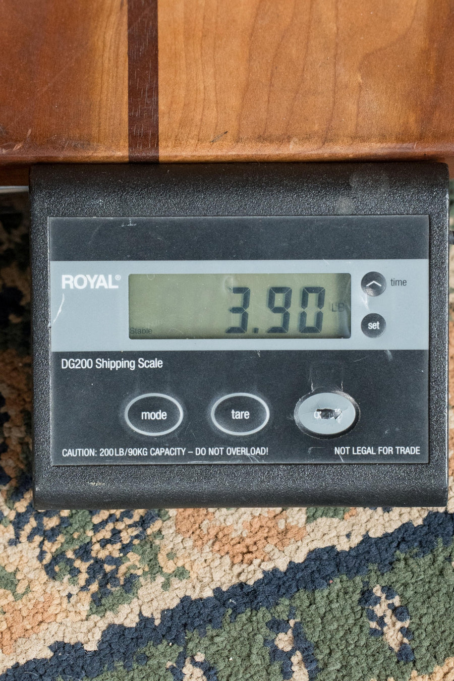 A digital shipping scale on a patterned carpet displays 3.90 lbs, partially covered by the *New 2025 Model* Martin D Jr E Streetlegend Burst Spruce/Sapele Aged-Look Dreadnought Guitar w/Martin Electronics #3868 from Martin & Co., highlighting its lightweight build.