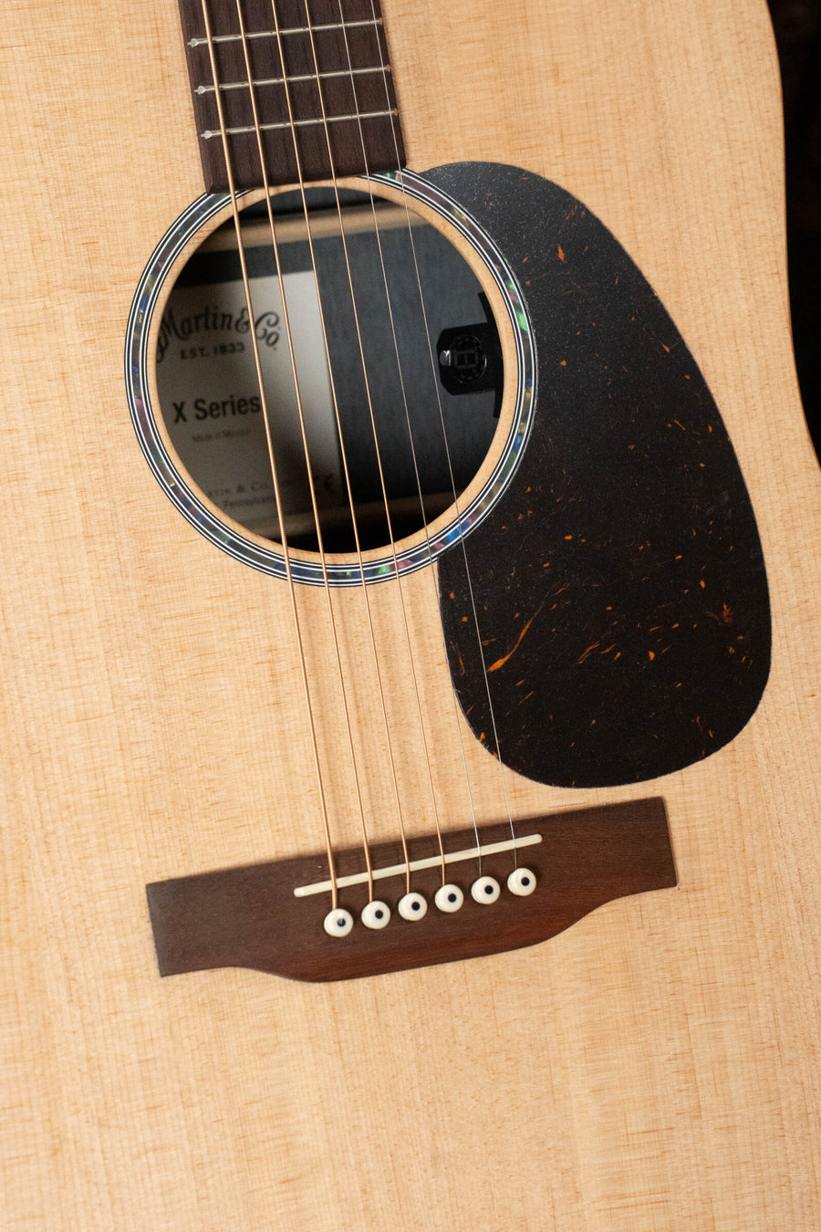 Close-up of a Martin & Co. D-X2E Sitka/HPL Brazilian Rosewood Dreadnought Guitar (#7868) showing the soundhole, bridge, part of the fretboard, and X Series label—a pro-quality acoustic with E-1 Pickup for great tone.