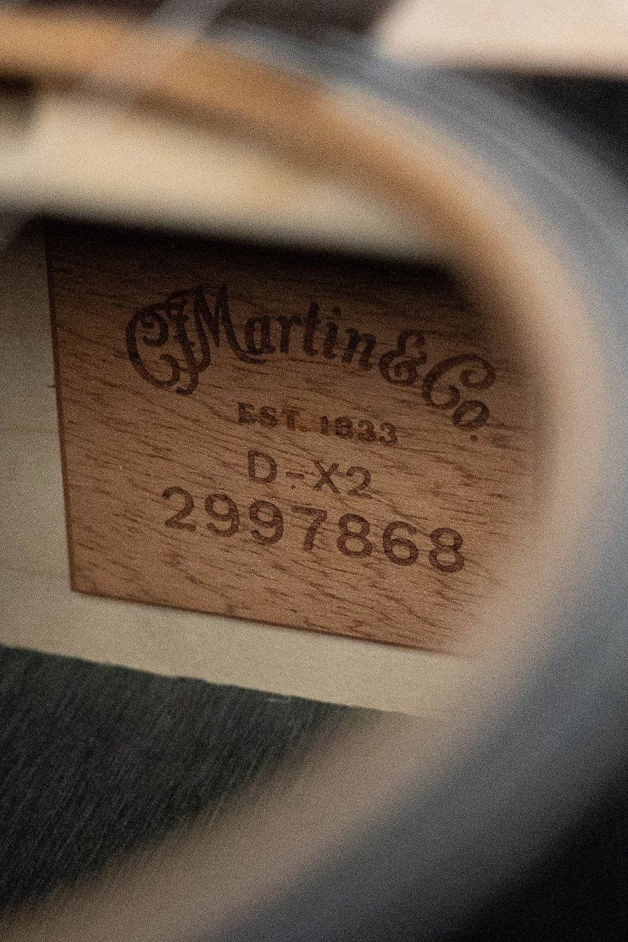 Close-up of the inside label of a Martin & Co. D-X2E Sitka/HPL Brazilian Rosewood Dreadnought Guitar w/ Martin E-1 Pickup #7868, engraved on wood and partially framed by the guitar's sound hole—a sign of quality craftsmanship.