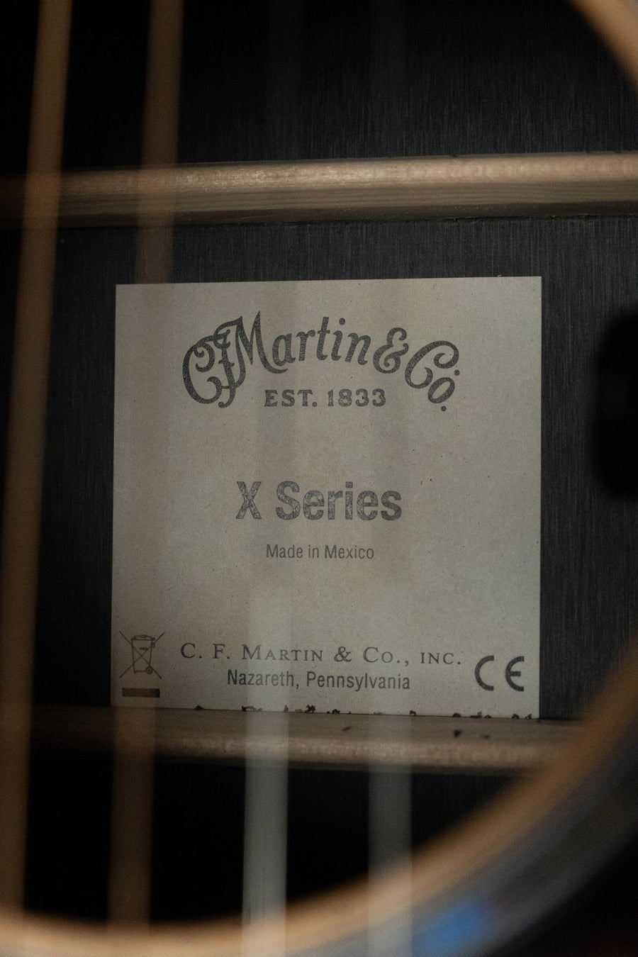 Close-up of the Martin & Co. D-X2E Sitka/HPL Brazilian Rosewood Dreadnought Guitar w/Martin E-1 Pickup #7868 label inside the sound hole, with "EST. 1833" and origin details visible among guitar strings and wood.