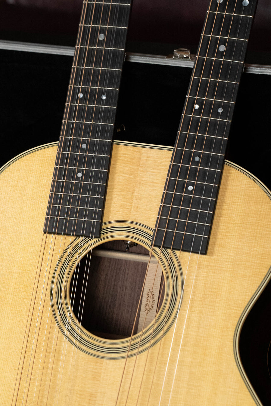 Close-up of the Martin & Co. Grand J-28E DN Spruce/Rosewood Double Neck Jumbo Guitar w/Fishman Pickup #3046, featuring two fretboards and multiple strings above a wooden body with a round sound hole.