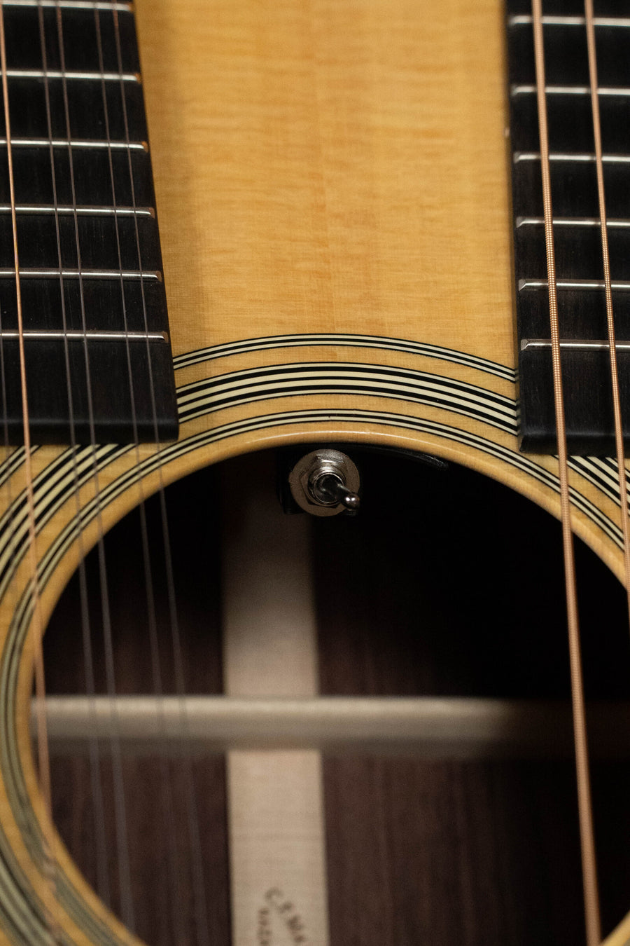 Close-up of the Martin & Co. Grand J-28E DN Spruce/Rosewood Double Neck Jumbo Guitar w/Fishman Pickup #3046, highlighting its sound hole, strings, wooden body, rosette detail, and the distinctive dual fretboards above the sound hole.