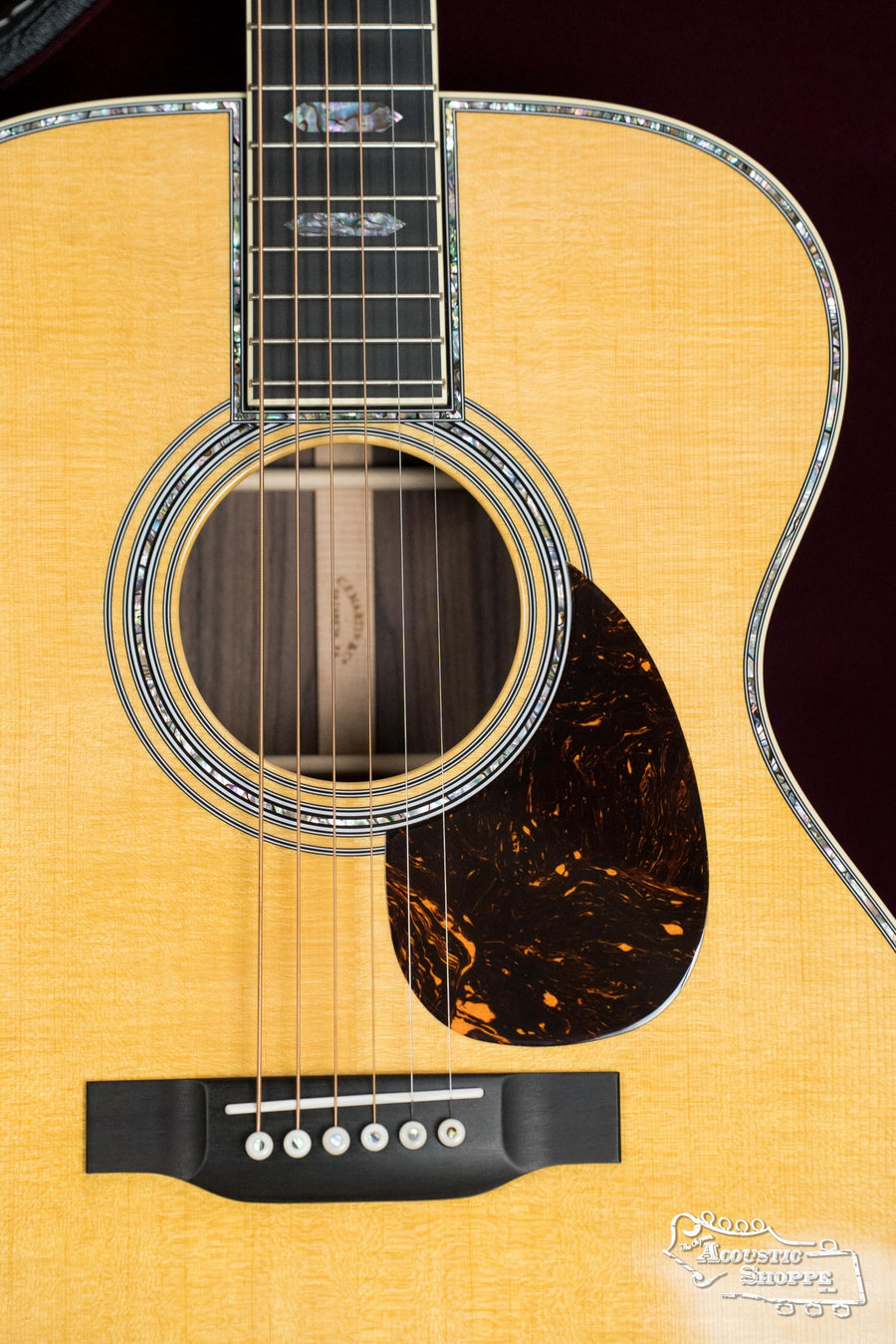 Close-up of a Martin & Co. *NEW 2025* OM-45 Spruce/Rosewood Acoustic Guitar #5120, highlighting abalone inlay on the soundhole and edges, tortoiseshell-patterned pickguard, six strings, and a light spruce rosewood finish.
