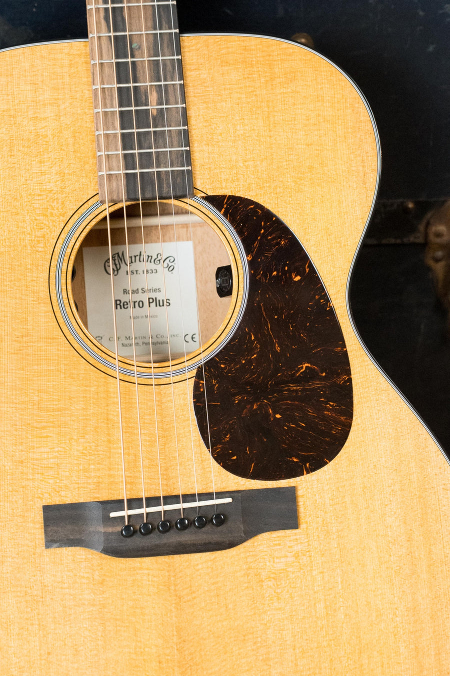 Close-up of the *New 2025 Model* Martin & Co. OOOE Retro Plus Guitar (#8194), showing its torrefied spruce top, mahogany body, strings, soundhole, tortoiseshell-style pickguard, and interior Martin label with built-in electronics.