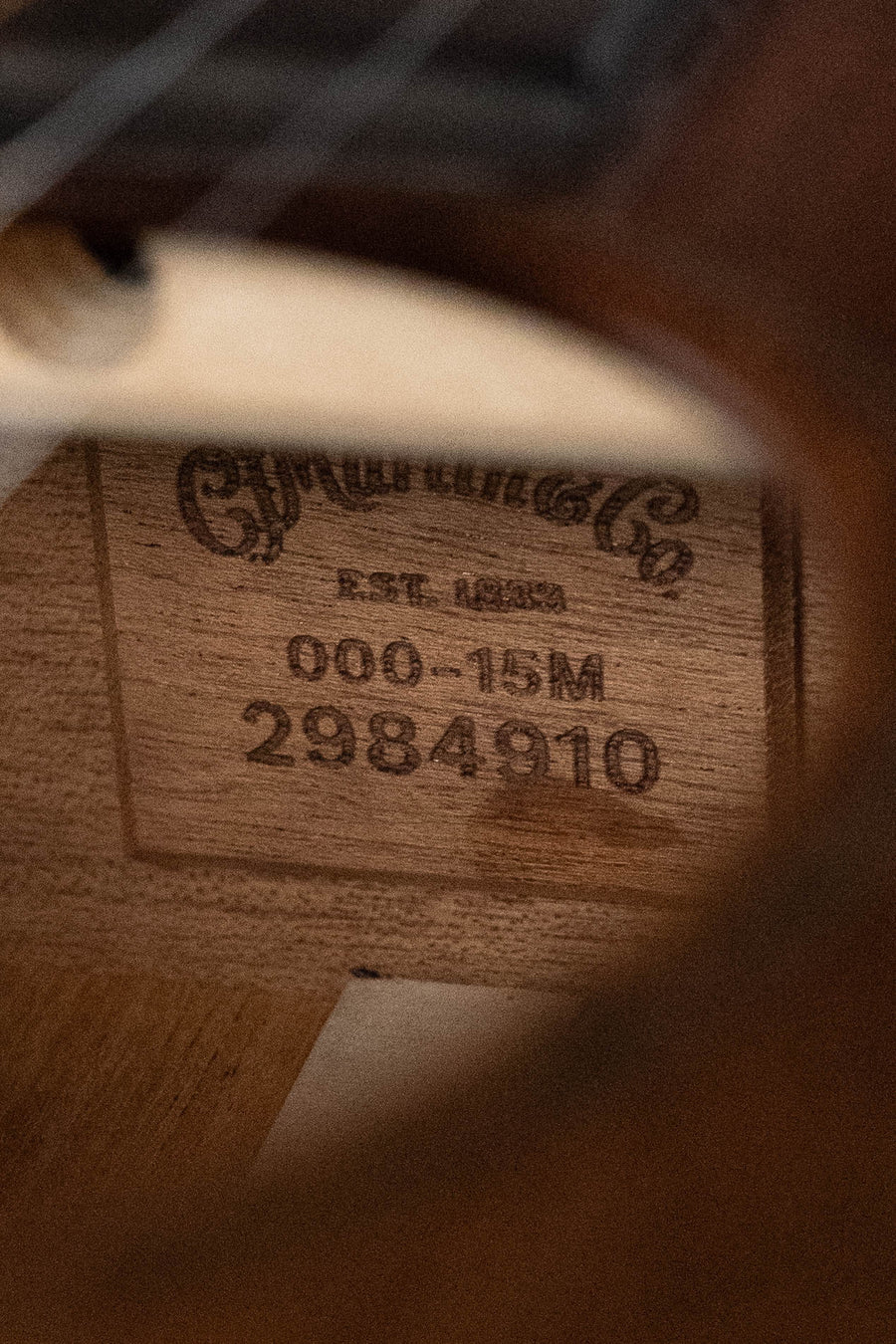 Close-up of the all-mahogany Martin & Co. OOO-15M StreetMaster acoustic guitar, with a label showing its craftsmanship and serial number #4910 inside the body.