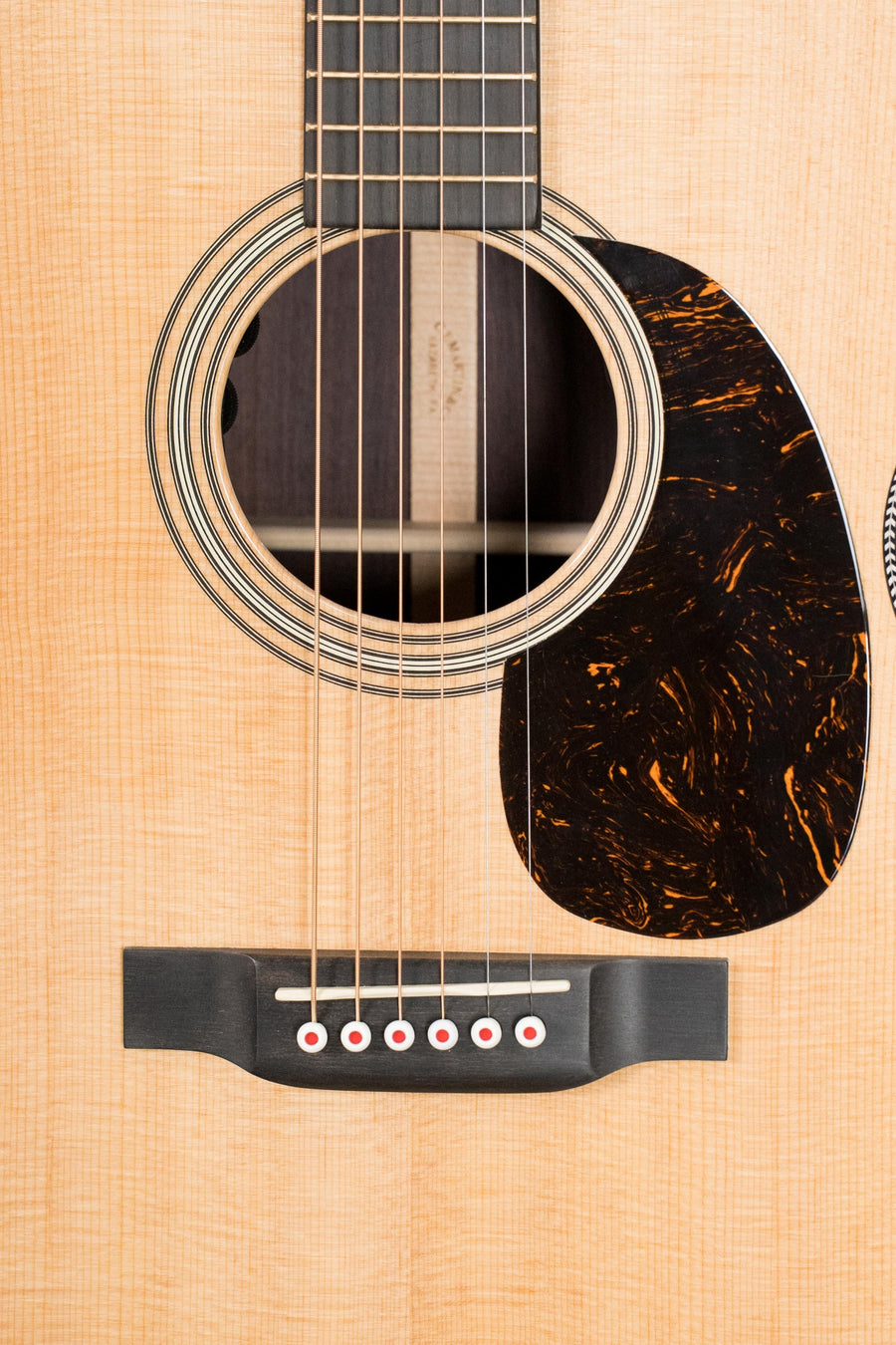 Close-up of a Martin & Co. OOO-28E Modern Deluxe guitar, showcasing its solid spruce top, detailed rosette, marbled dark pickguard, six bridge pins, and classic styling—Model Spruce/Indian Rosewood OOO Guitar w/Electronics #6398.