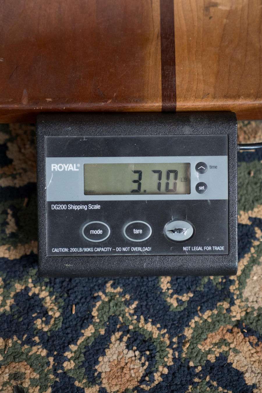 A digital shipping scale on a patterned rug reads 3.70 lbs, with part of a Martin & Co. OOO Jr CE Spruce/Sapele Cutaway Guitar w/Martin Electronics (#4755) resting on top.