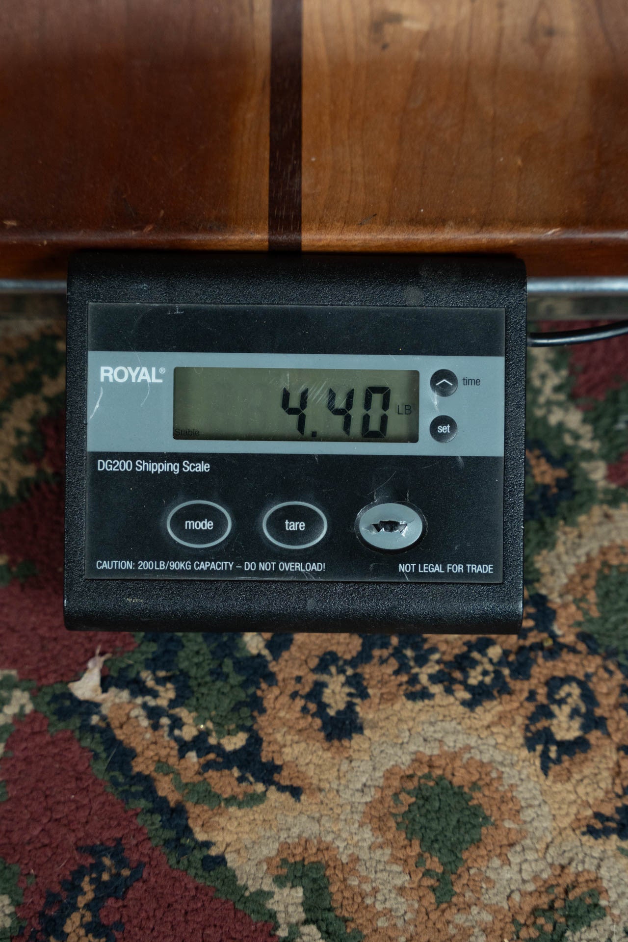 A digital shipping scale on a patterned carpet displays 4.40 pounds, possibly weighing a Maton Guitars T.E. Personal Spruce/Queensland Maple Deep Body OO Guitar w/Electronics #0085.