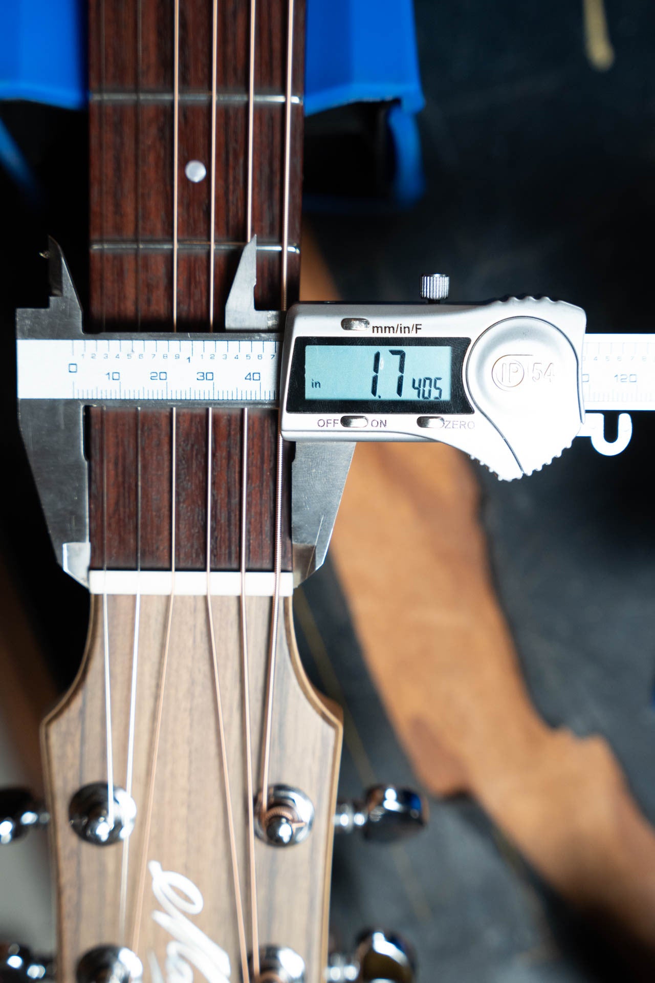 A digital caliper measures the nut width of the Maton Guitars T.E. Personal Spruce/Queensland Maple Deep Body OO Guitar w/Electronics #0085 at 1.7405 inches; it has six strings and a wooden headstock with metal tuners.