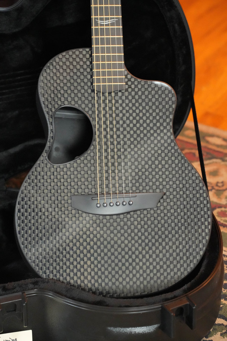 The McPherson Guitars Carbon Fiber Touring Series Blackout Basketweave Guitar w/L.R. Baggs Element Pickup #0061 features gold tuners and a sleek black case, making it the perfect touring companion for musicians on the go.