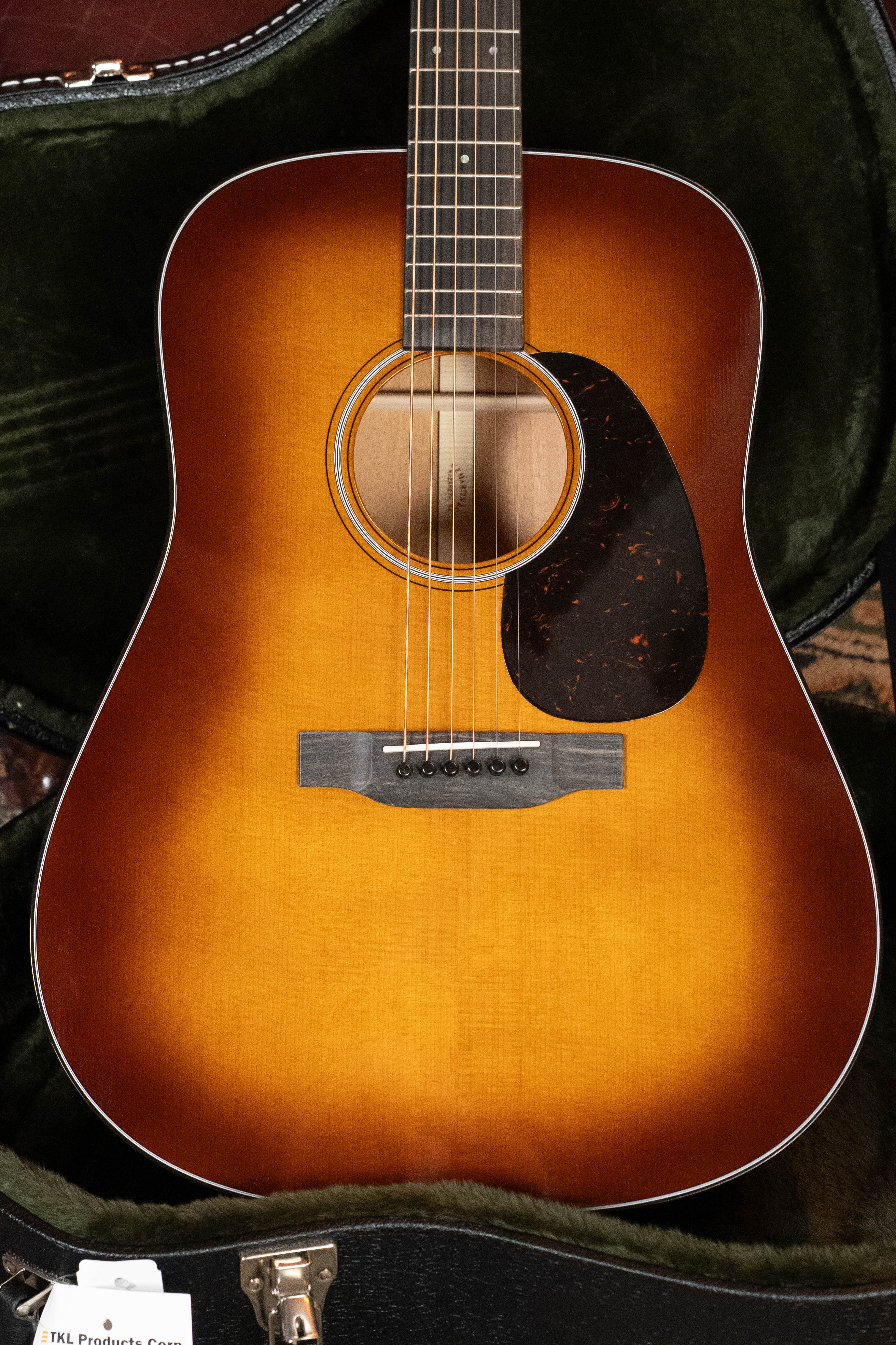 The *New 2025 Model* Martin D-18 1933 Gloss Ambertone Spruce/Mahogany Dreadnought by Martin & Co. features a sunburst finish, dark tortoiseshell pickguard, GE-scalloped X-bracing, wood bridge, and green plush-lined hard case.
