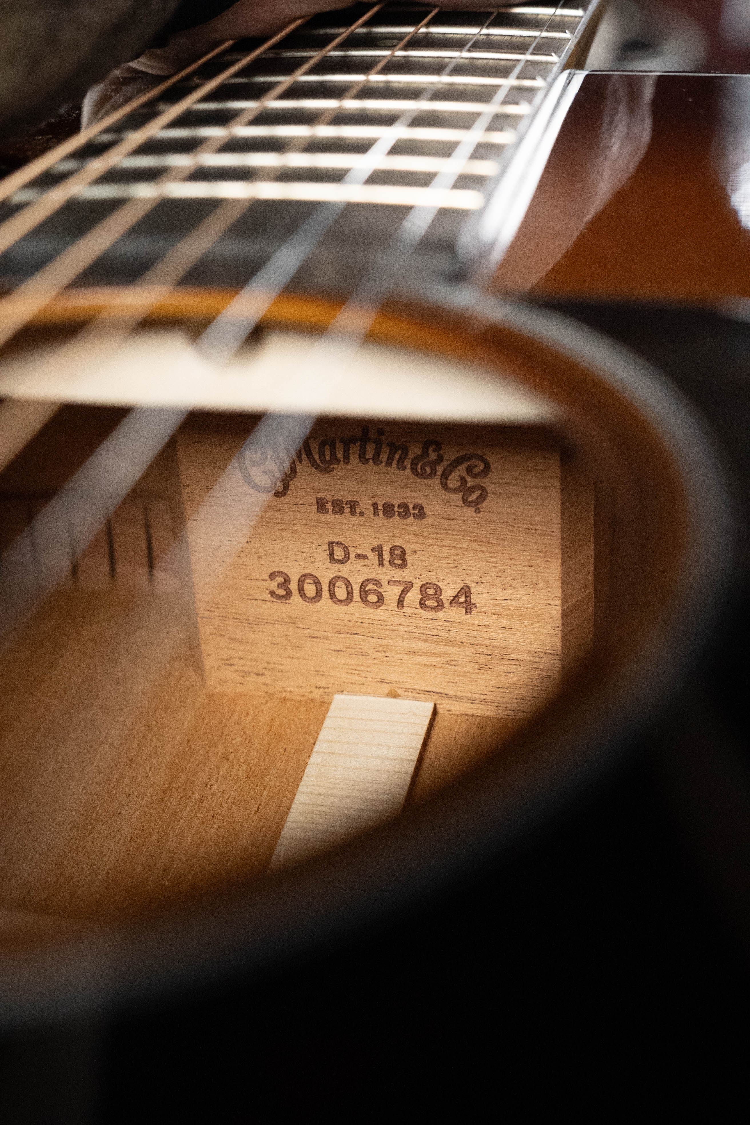 Close-up through the sound hole of a *New 2025 Model* Martin D-18 1933 Gloss Ambertone Spruce/Mahogany Dreadnought Acoustic Guitar #6784 by Martin & Co.; label, strings, fretboard, and hints of X-bracing are visible.