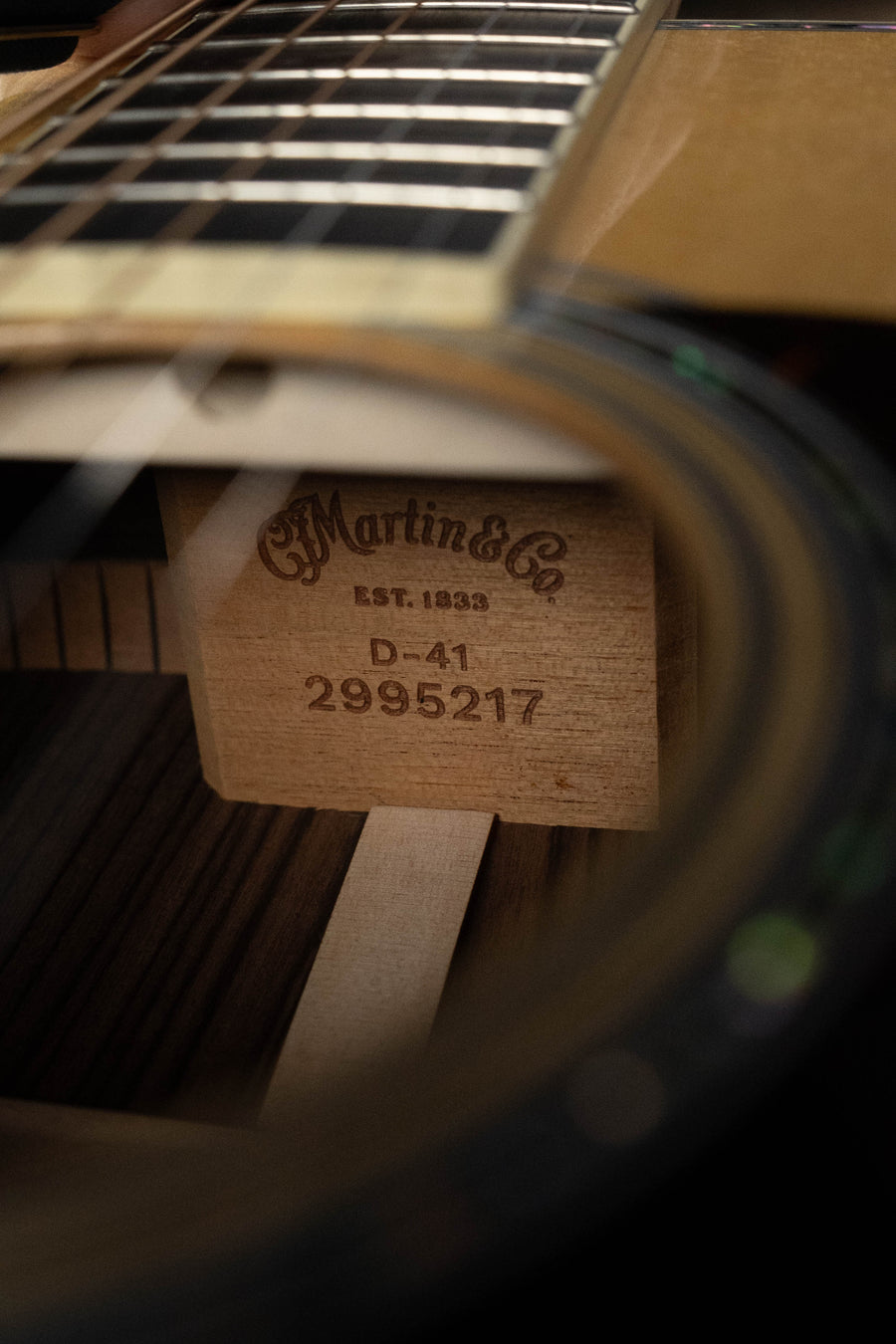 A close-up through the sound hole of a Martin & Co. D-41 Spruce/Indian Rosewood Dreadnought Acoustic Guitar #5217 reveals the internal stamp on the wood block inside its body.