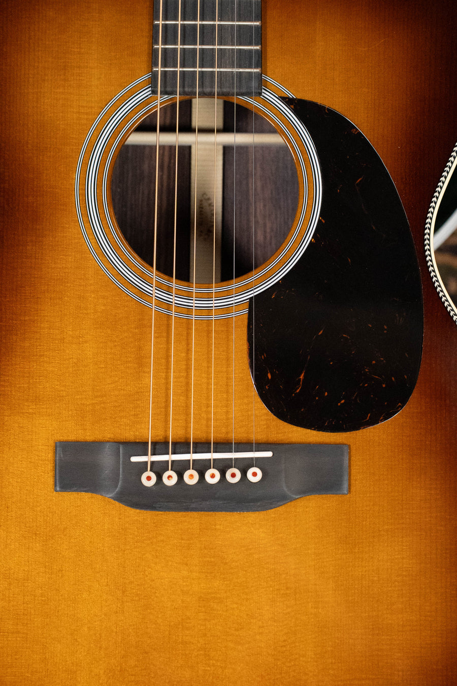 Close-up of the Martin & Co. OOO-28 Gloss 1933 Ambertone Spruce/Rosewood Acoustic Guitar #3434, highlighting its strings, rosette, soundhole, pickguard, and bridge on a warm brown East Indian rosewood finish.