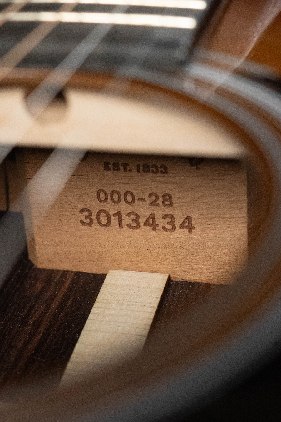 Close-up of a Martin & Co. OOO-28 Gloss 1933 Ambertone Spruce/Rosewood acoustic guitar (#3434) sound hole, showing model and serial number stamped on East Indian rosewood inside, with visible strings and fretboard.