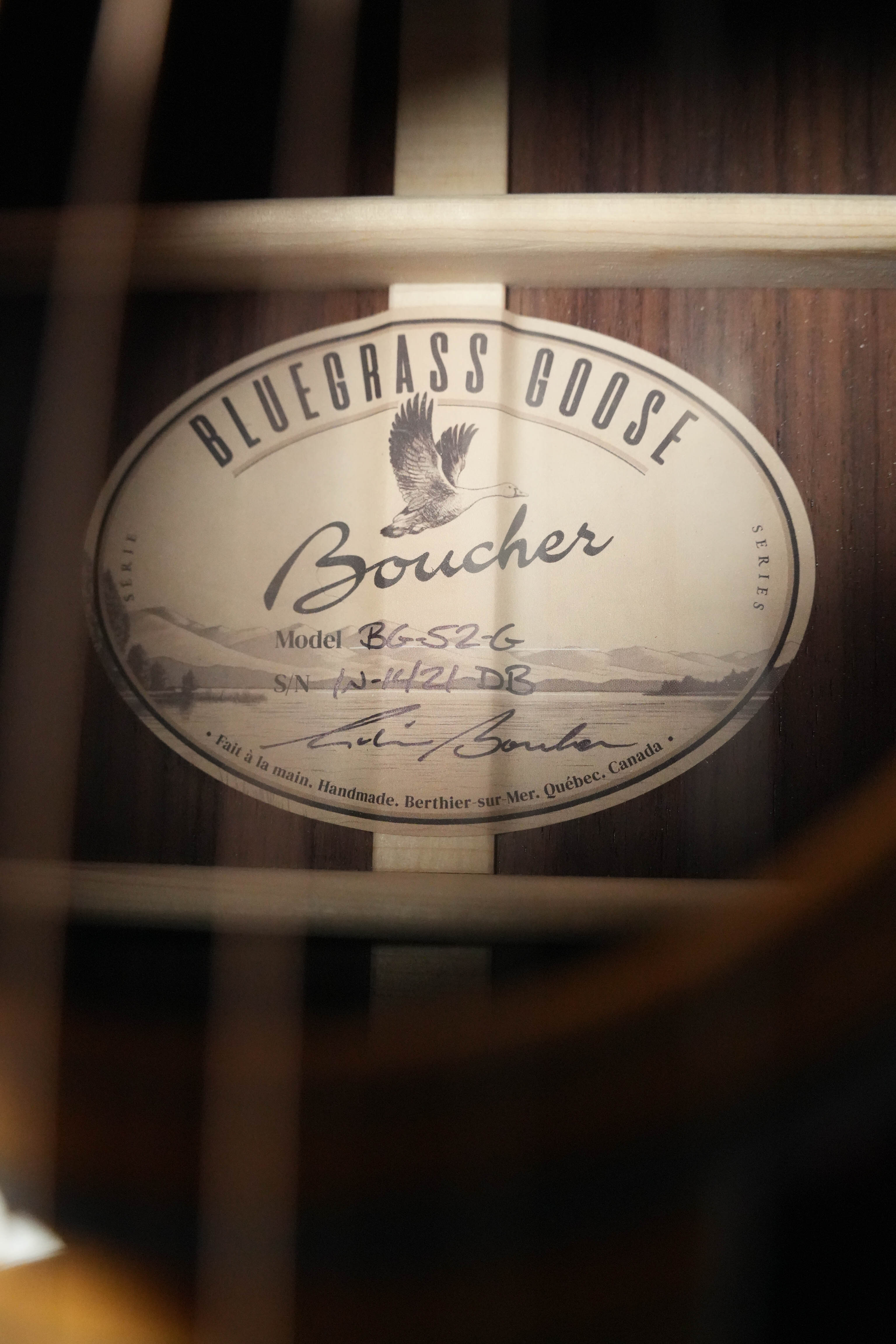 Close-up of a Boucher Guitars label inside the *New 2026 Model* BG-52-G Torrefied Adirondack/Rosewood Bluegrass Goose Gold Pack Dreadnought #1421, featuring model details, a goose illustration, and a handwritten signature.