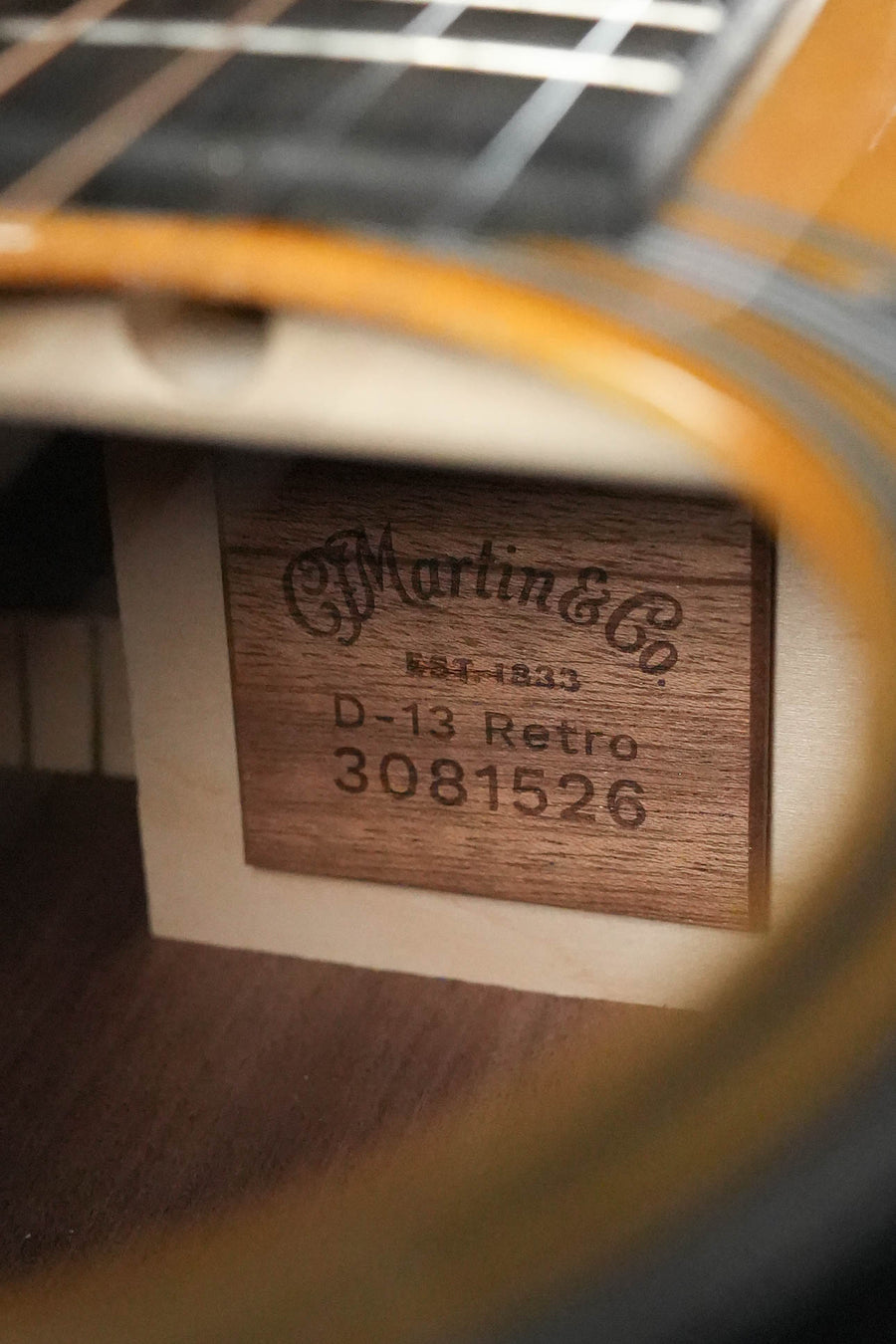 Close-up of the inside of a Martin & Co. *New 2026 Model* D-13E Retro Road Series dreadnought guitar w/Martin Electronics #1526, showing a wooden label with product info through the sound hole.