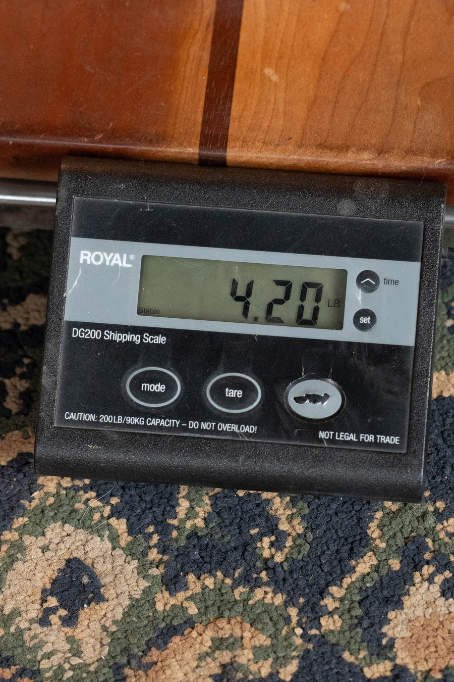 A digital shipping scale on a patterned carpet shows a *New 2026 Model* Martin & Co. OMC-10E Modern Burst Road Series Spruce/Sapele Cutaway Guitar w/Martin Electronics #9948 weighing 4.20 lbs; the scale has mode, tare, set buttons and max capacity warning.