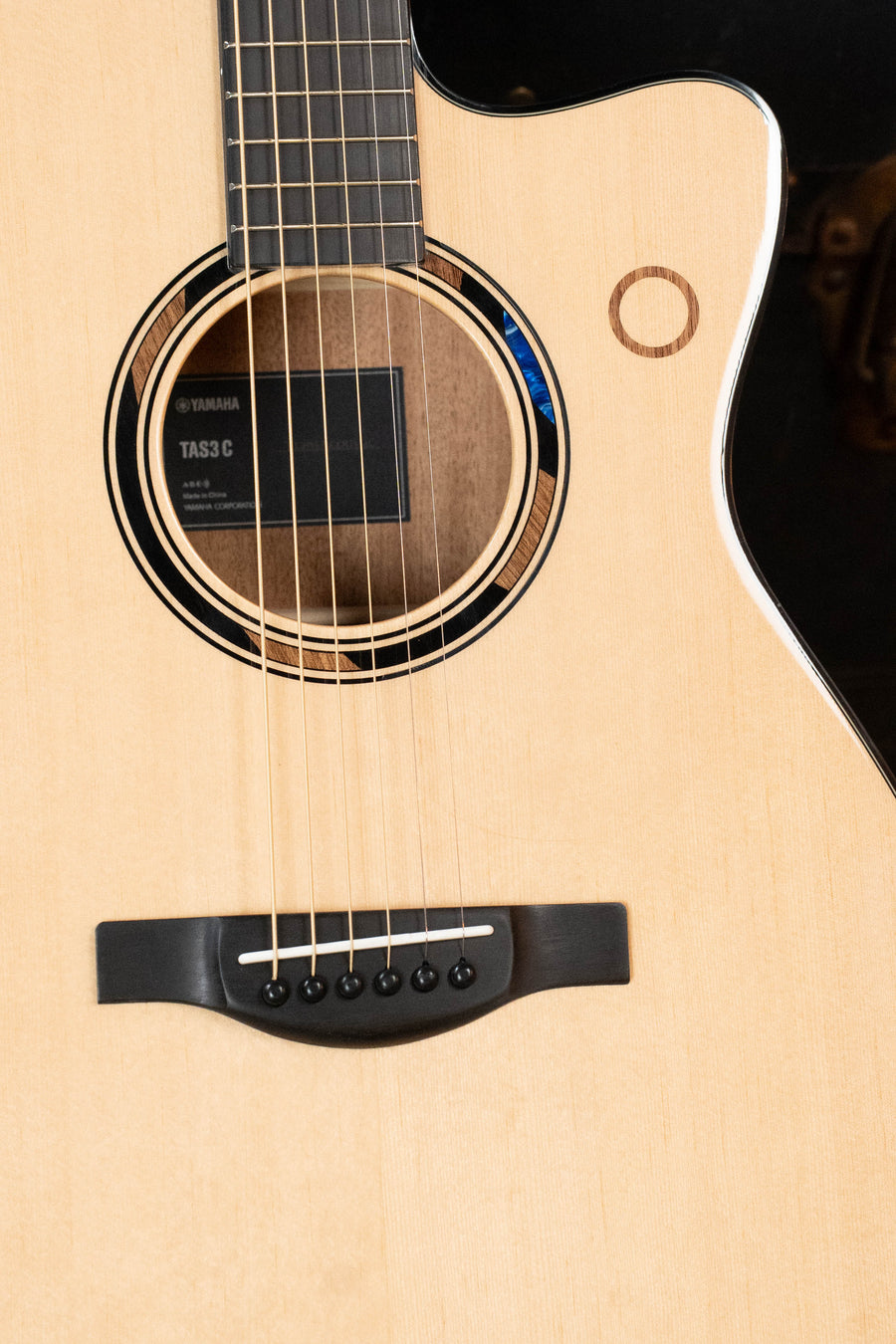Close-up of the *New 2026 Model* Yamaha TAS3C-NT Concert Guitar’s body, with Yamaha label in the sound hole, strings, bridge, upper bout cutaway, and solid Sitka spruce top—featuring the NEWEST TransAcoustic System.