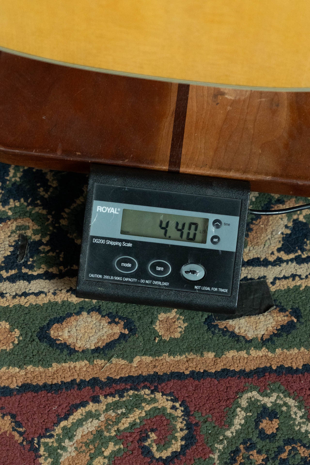 A digital shipping scale reads 4.40 pounds as it sits on a patterned rug, partly under the *New 2025 Model* Martin D-28 Gloss Spruce/Indian Rosewood Dreadnought Acoustic Guitar #0650 by Martin & Co.