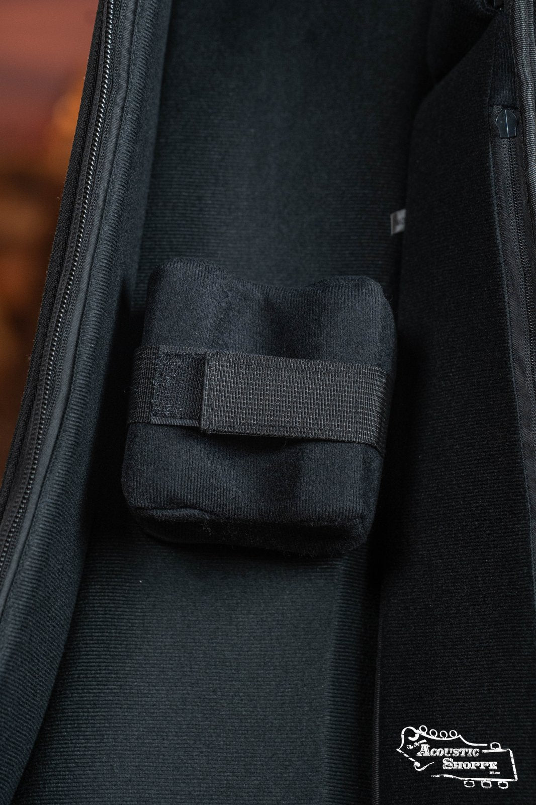 Close-up of a black padded strap inside the Ortega OSOCABJ-MO Banjo Soft Case in Mocca, featuring soft fabric lining and the Ortega logo in the bottom right corner.