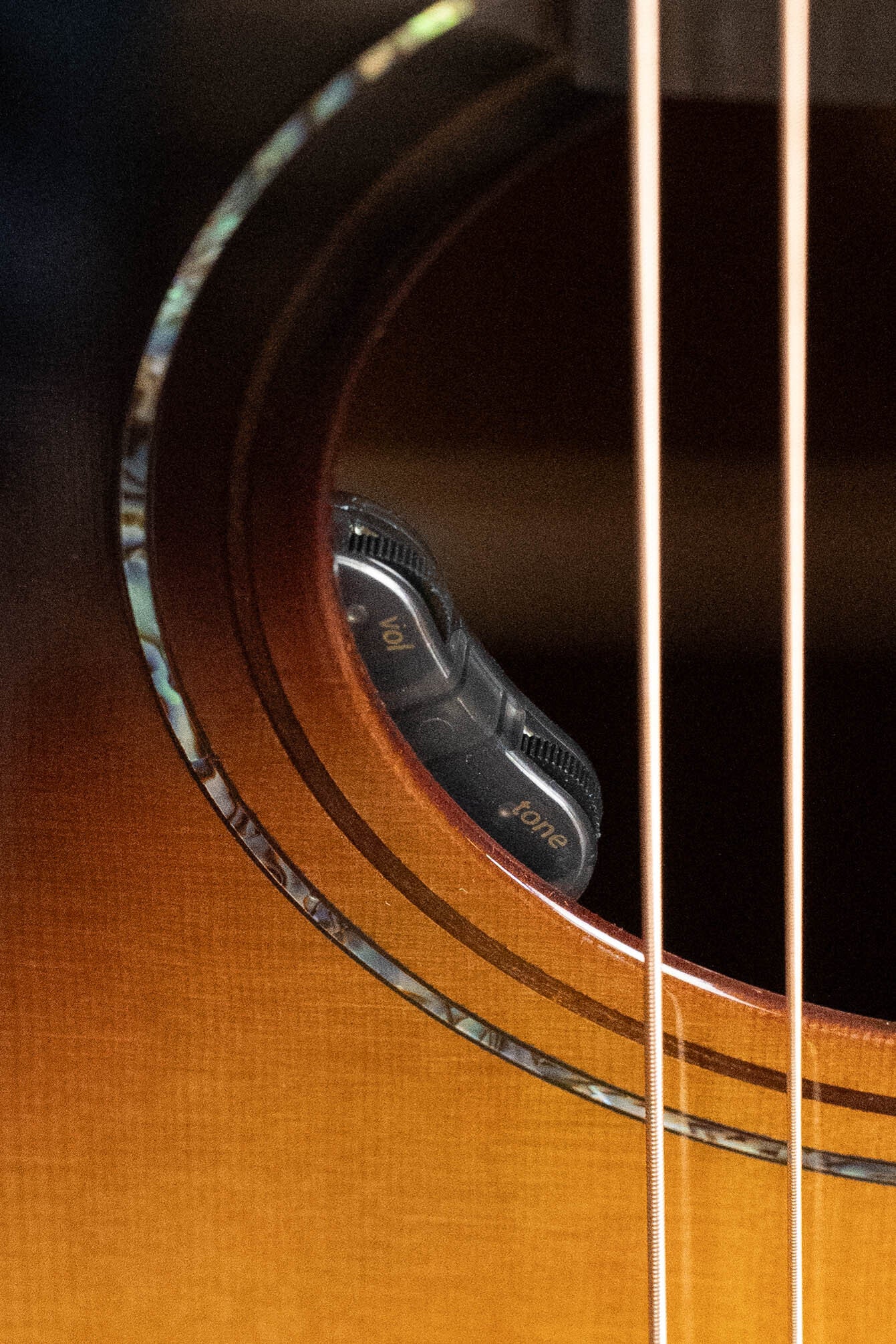 Close-up of the Alvarez Masterworks JP Cormier Signature Slope Shoulder 12th Fret Dreadnought w/Cutaway (#7291) by Alvarez, showing two black vol and tone control knobs inside the Adirondack spruce top, with strings visible in front.