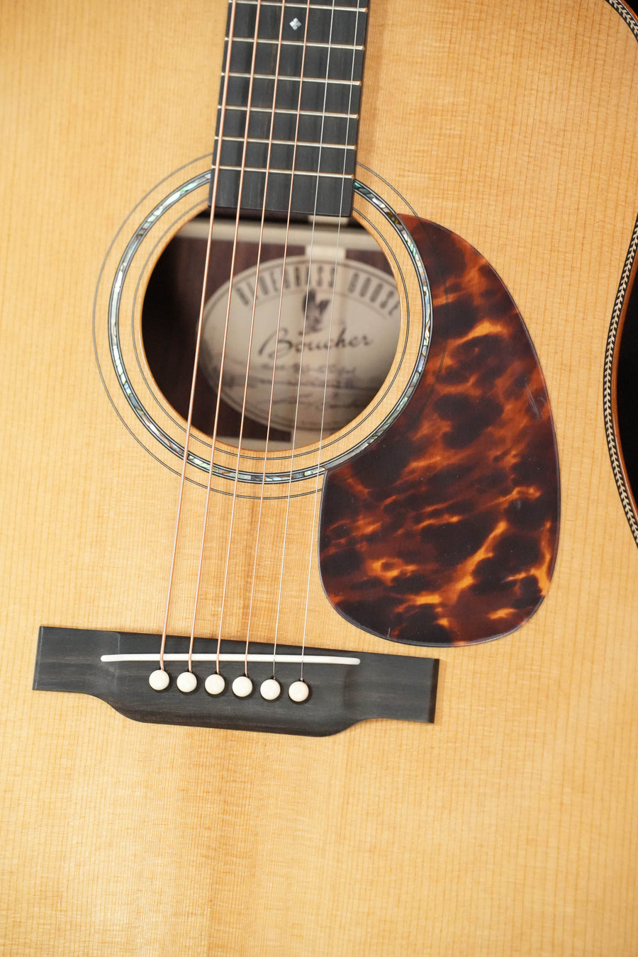 Close-up of the Boucher Guitars *Stage Ready* BG-52-GM Bluegrass Goose Gold Master Pack Dreadnought #1415, showing the sound hole, strings, tortoiseshell pickguard, bridge, and label—no visible cosmetic imperfections.