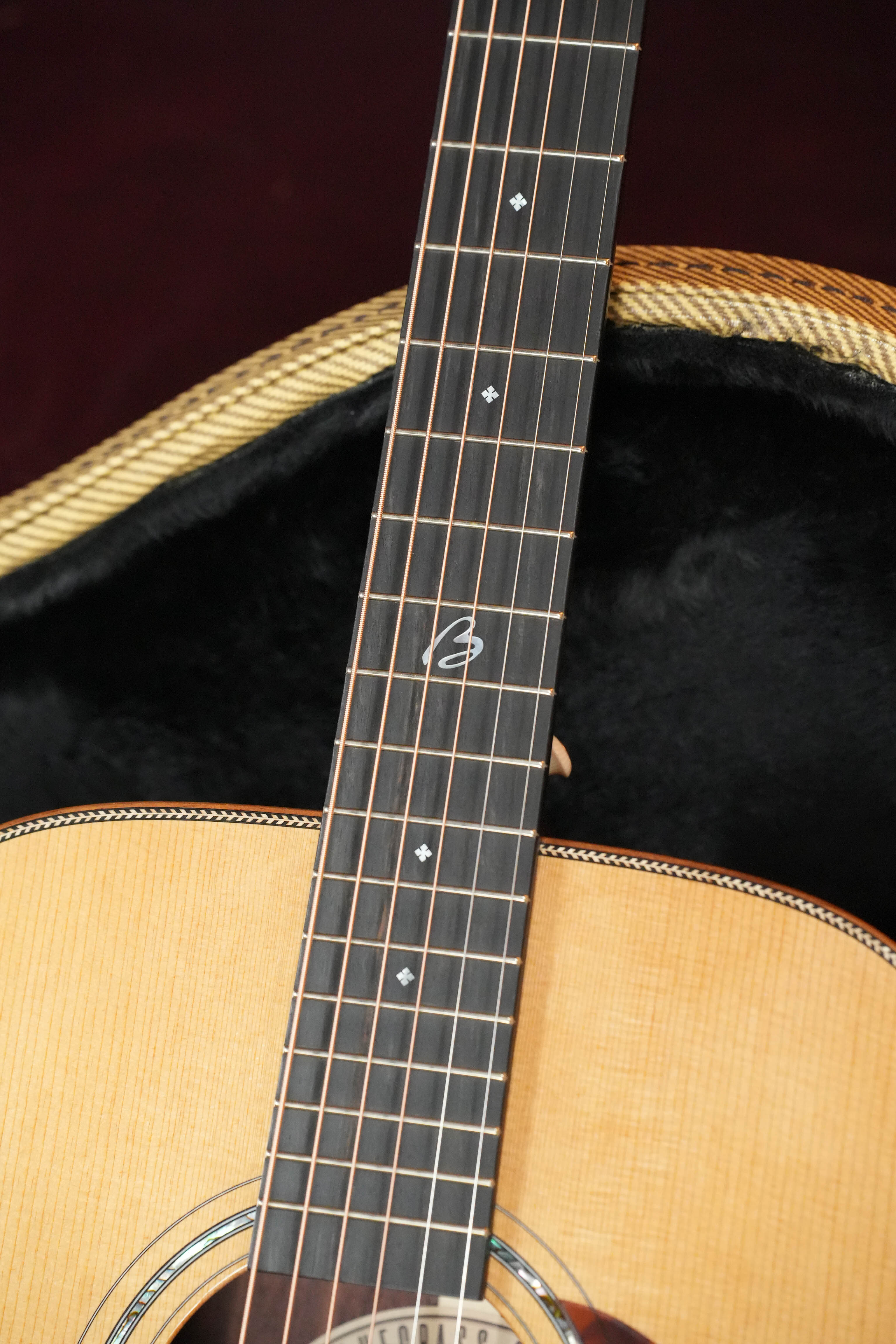 Close-up of the *Stage Ready* Boucher BG-52-GM Bluegrass Goose Gold Master Pack Dreadnought by Boucher Guitars, showing its torrefied Adirondack fretboard with mother-of-pearl inlays, resting in an open black-lined case.