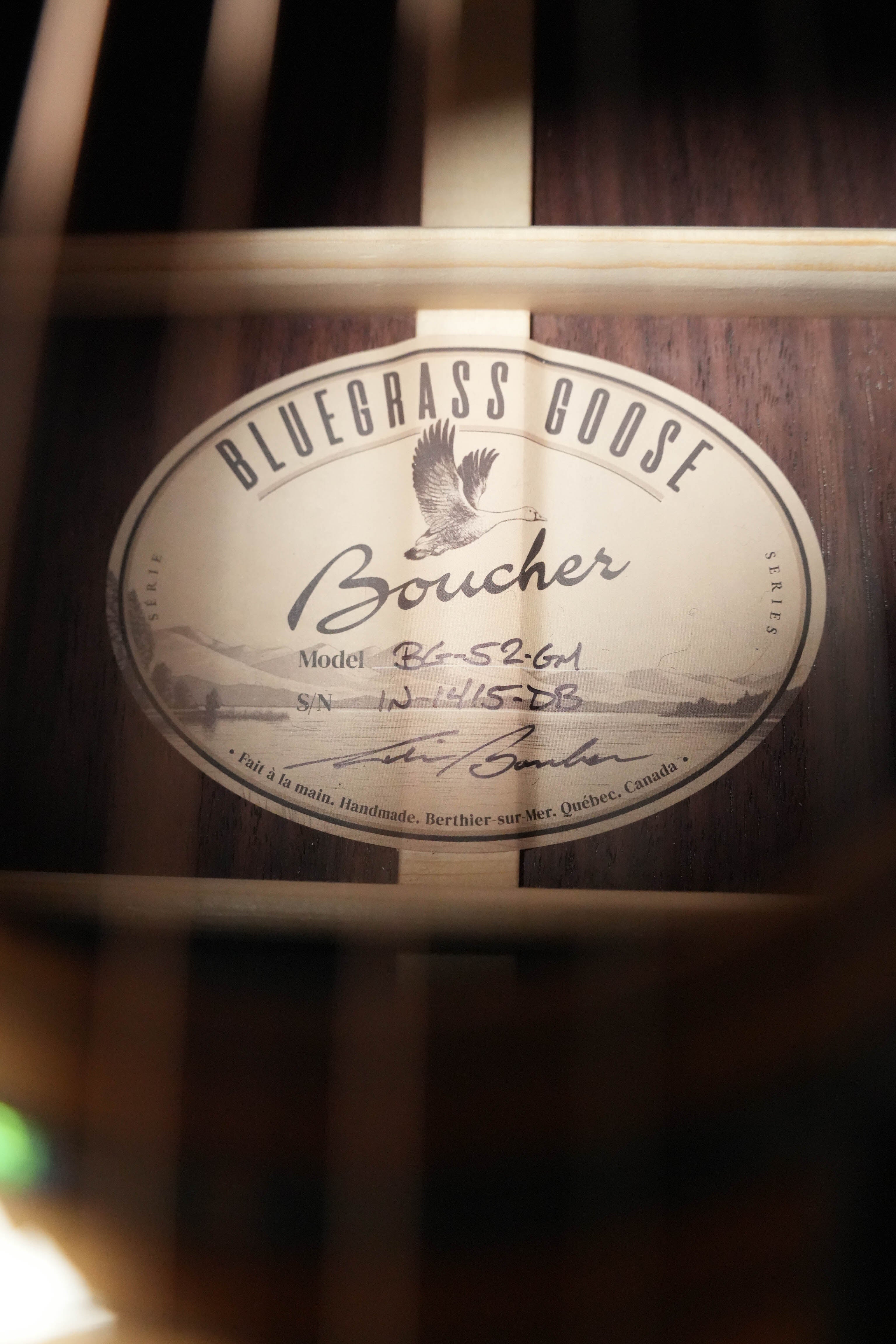 Close-up of the label inside a brand-new Boucher Guitars *Stage Ready* BG-52-GM Torrefied Adirondack/Rosewood Bluegrass Goose Gold Master Pack Dreadnought Acoustic Guitar #1415, showing handwritten model and serial details plus wooden bracing. No cosmetic imperfections.