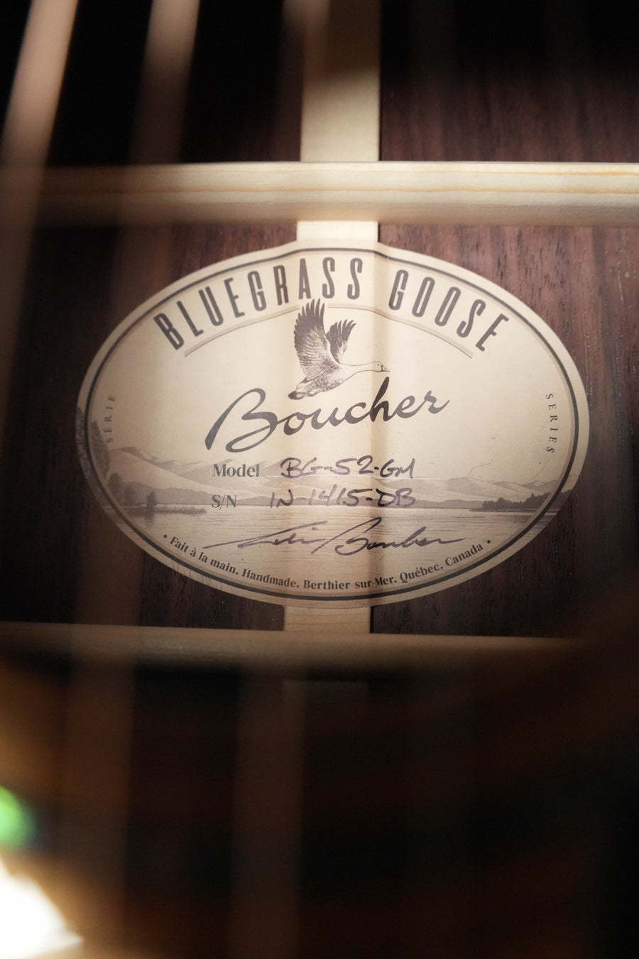Close-up of the label inside a brand-new Boucher Guitars *Stage Ready* BG-52-GM Torrefied Adirondack/Rosewood Bluegrass Goose Gold Master Pack Dreadnought Acoustic Guitar #1415, showing handwritten model and serial details plus wooden bracing. No cosmetic imperfections.