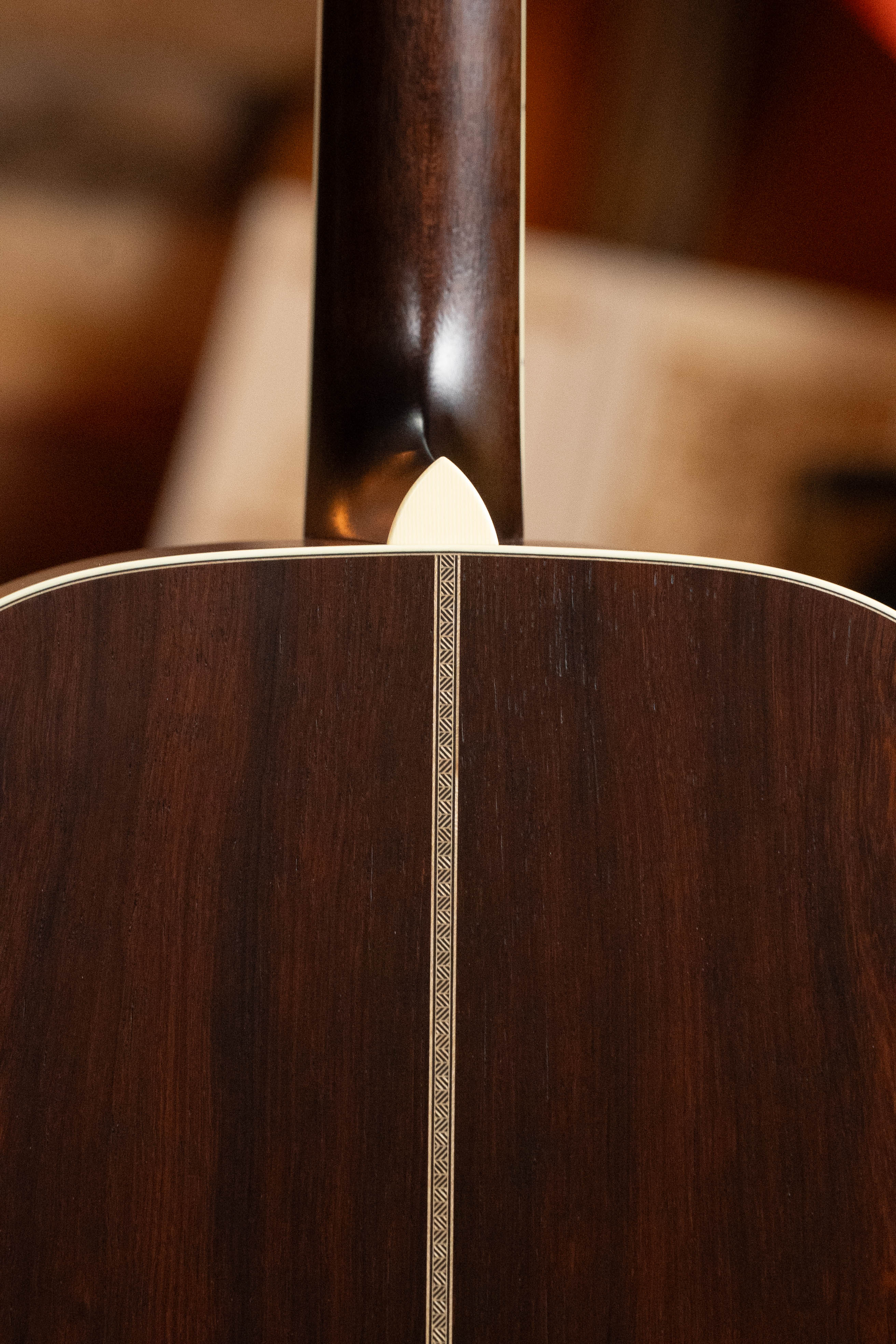 Close-up of the Bourgeois TAS LSH Professional Series Satin Dreadnought Guitar’s back features dark wood grain, a decorative center strip inlay, and cream binding at the neck joint. *Pre-Order 25% Deposit ONLY* required.