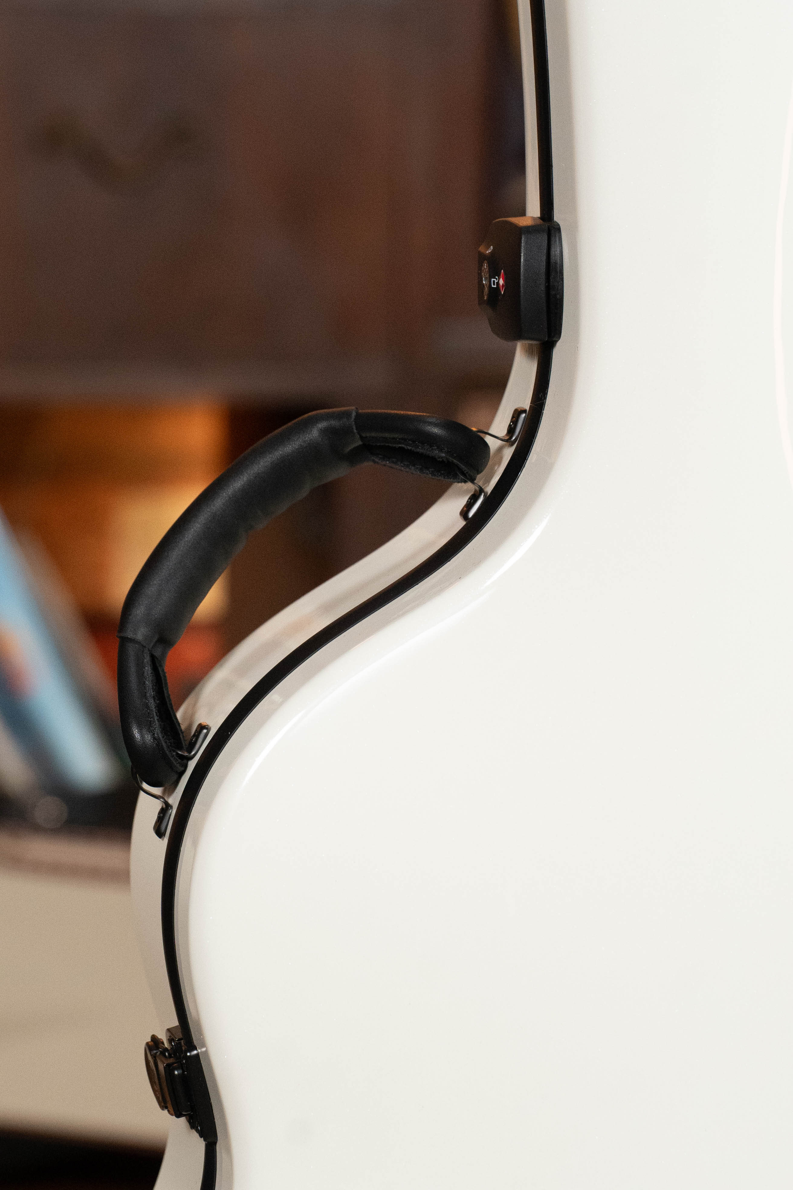 Close-up of the black handle on the TKL Voyager Universal Pearl Glacier/Blue Carbon Fiber Dreadnought Case, a lightweight, glossy white case by TKL. Perfect for touring musicians needing durable, reliable protection for their instrument on the go.