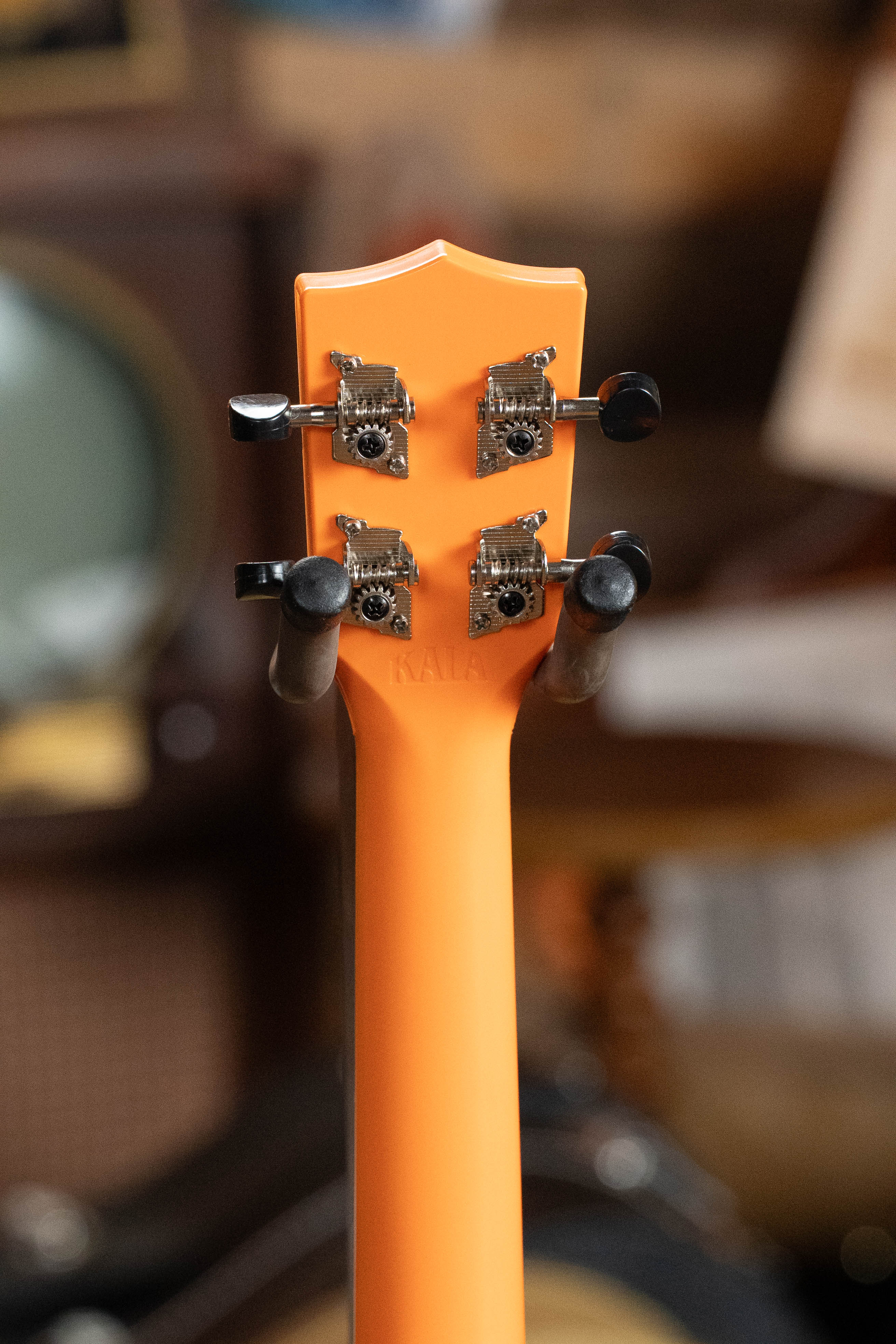 Sunset orange soprano ukulele neck and back with chrome tuning pegs on warm wood background. - The Waterman Sunset Orange Soprano Recycled Ukulele - Kala Brand - Default Title