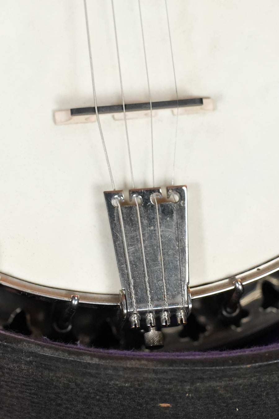 Close-up of a (Used) 1928 Bacon Style C Maple/Mahogany Resonator Banjo #2530, showing the metal tailpiece, strings, white drumhead, circular body, mahogany neck by Bacon, and part of the bridge.