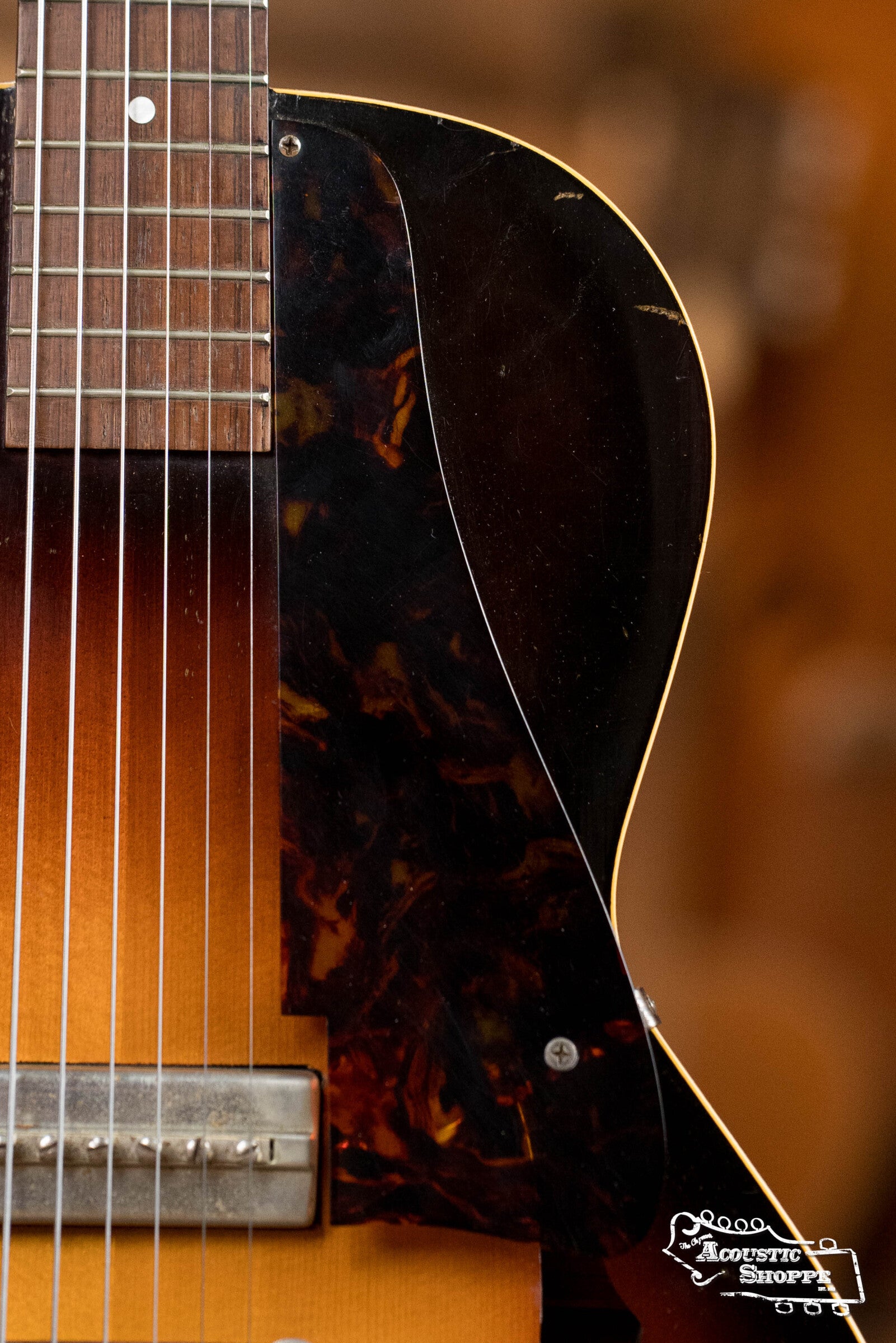 Close-up of the body of a (Used) 1942 Gibson ES-125 by Gibson, capturing its warm wooden finish, dark pickguard, strings, and bridge details—highlighting the vintage texture and craftsmanship of this classic hollow-body guitar.