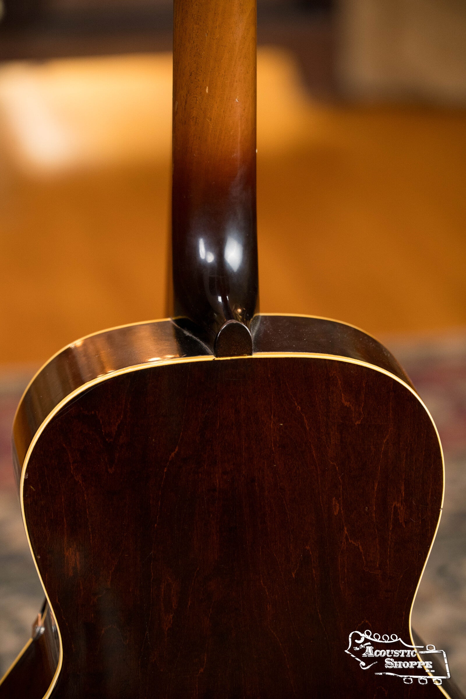 Close-up of the back and neck of a (Used) 1942 Gibson ES-125 by Gibson, featuring a dark wood finish, light binding, and a warm background. The Acoustic Shoppe logo appears in the lower right corner.