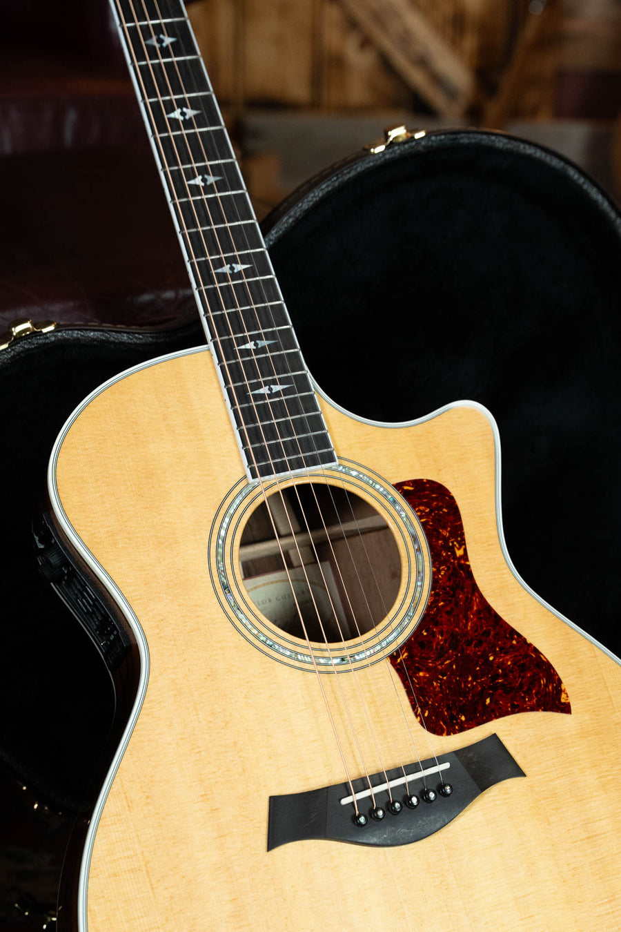 A close-up of a (Used) 1999 Taylor Guitars 814-BCE 25th Anniversary Sitka/Rosewood Grand Auditorium with electronics (#4124), in a natural finish, partially resting in an open black case.