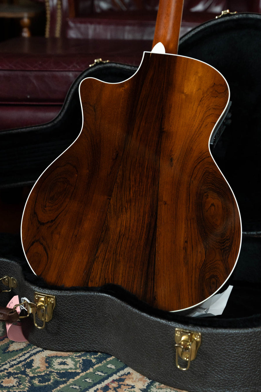 The image features a (Used) 1999 Taylor 814-BCE 25th Anniversary Grand Auditorium guitar, with glossy Sitka spruce top and dark rosewood back, in an open black hard case. White binding accents the edges.